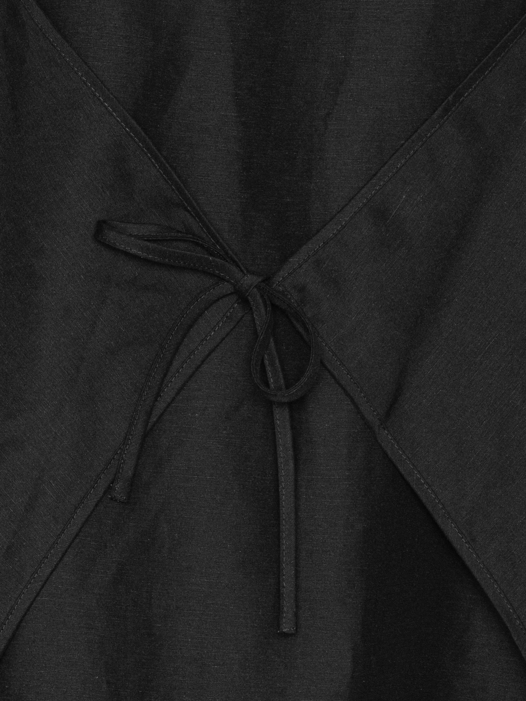 Closeup of Henrik Vibskov Beetle Dress in black, highlighting adjustable tie detail at front or back and textured fabric of SS26 design.