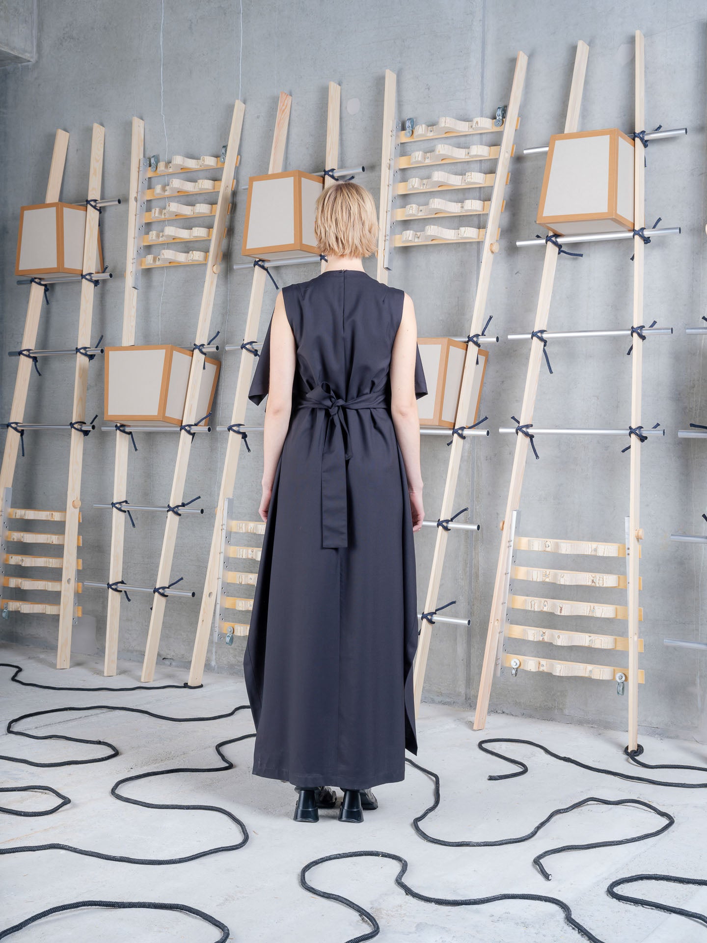 Model wearing the Henrik Vibskov Blanket Dress in black, back view showing the tie belt