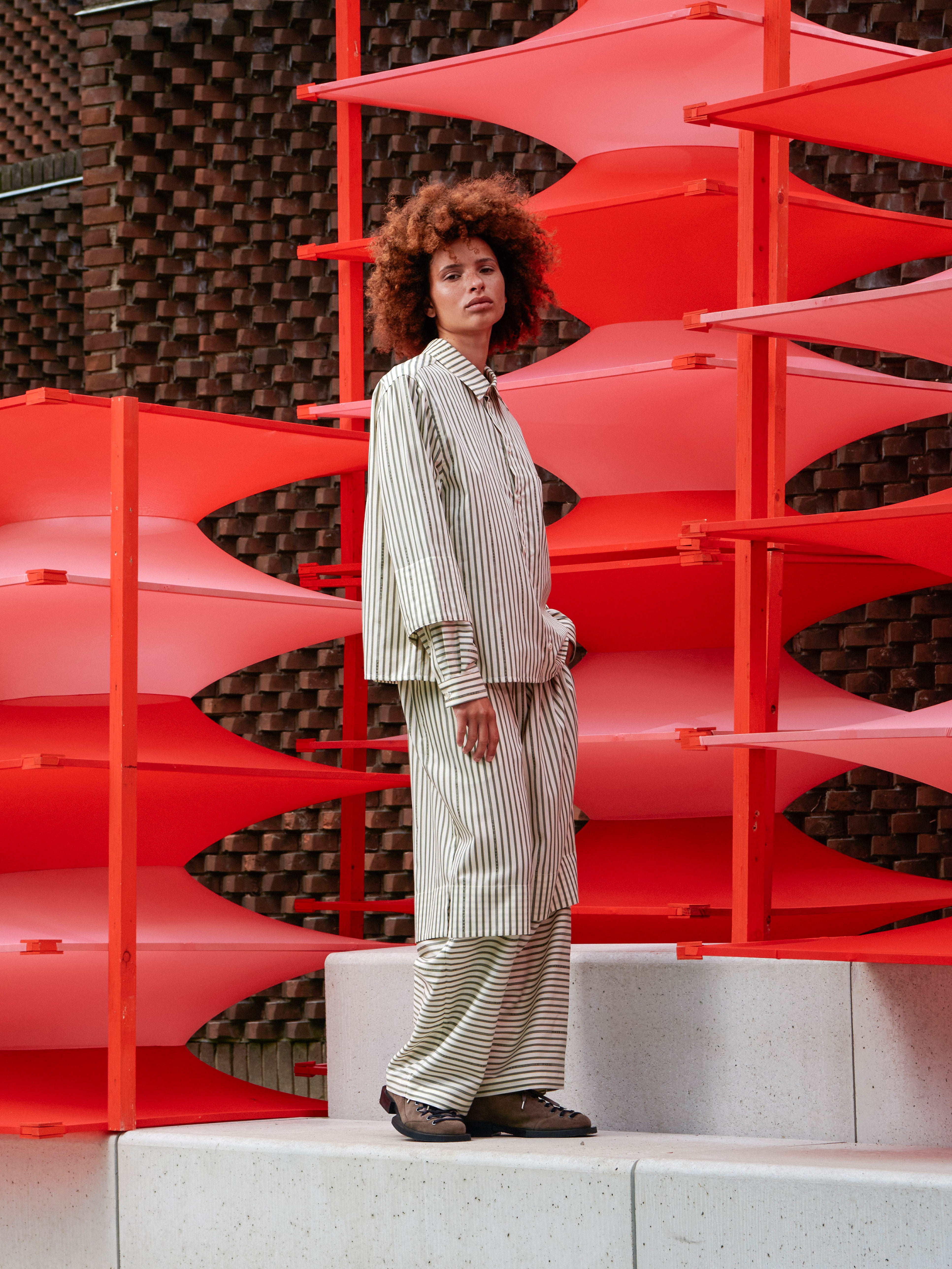 Side view of the model wearing the striped shirt, emphasizing layered sleeves and straight hem.