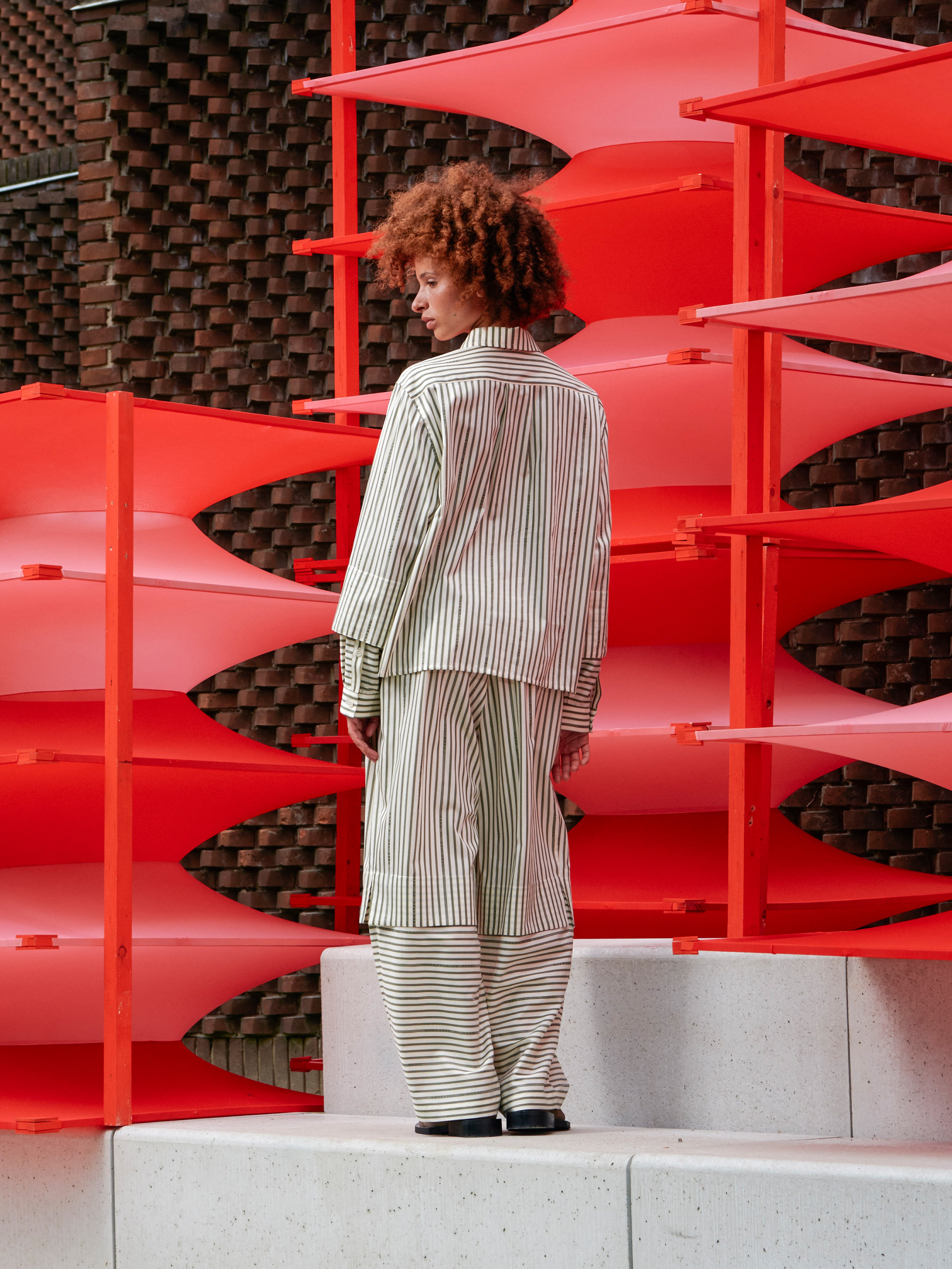 Back view of the model wearing the Blousse Shirt, highlighting the relaxed silhouette and continuous striped pattern.