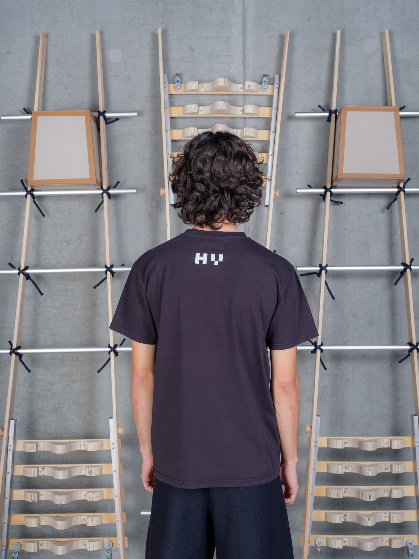 Back view of a male model wearing the Henrik Vibskov Cross Stitch Tee in Black, highlighting the clean rear design, short sleeves, and relaxed silhouette