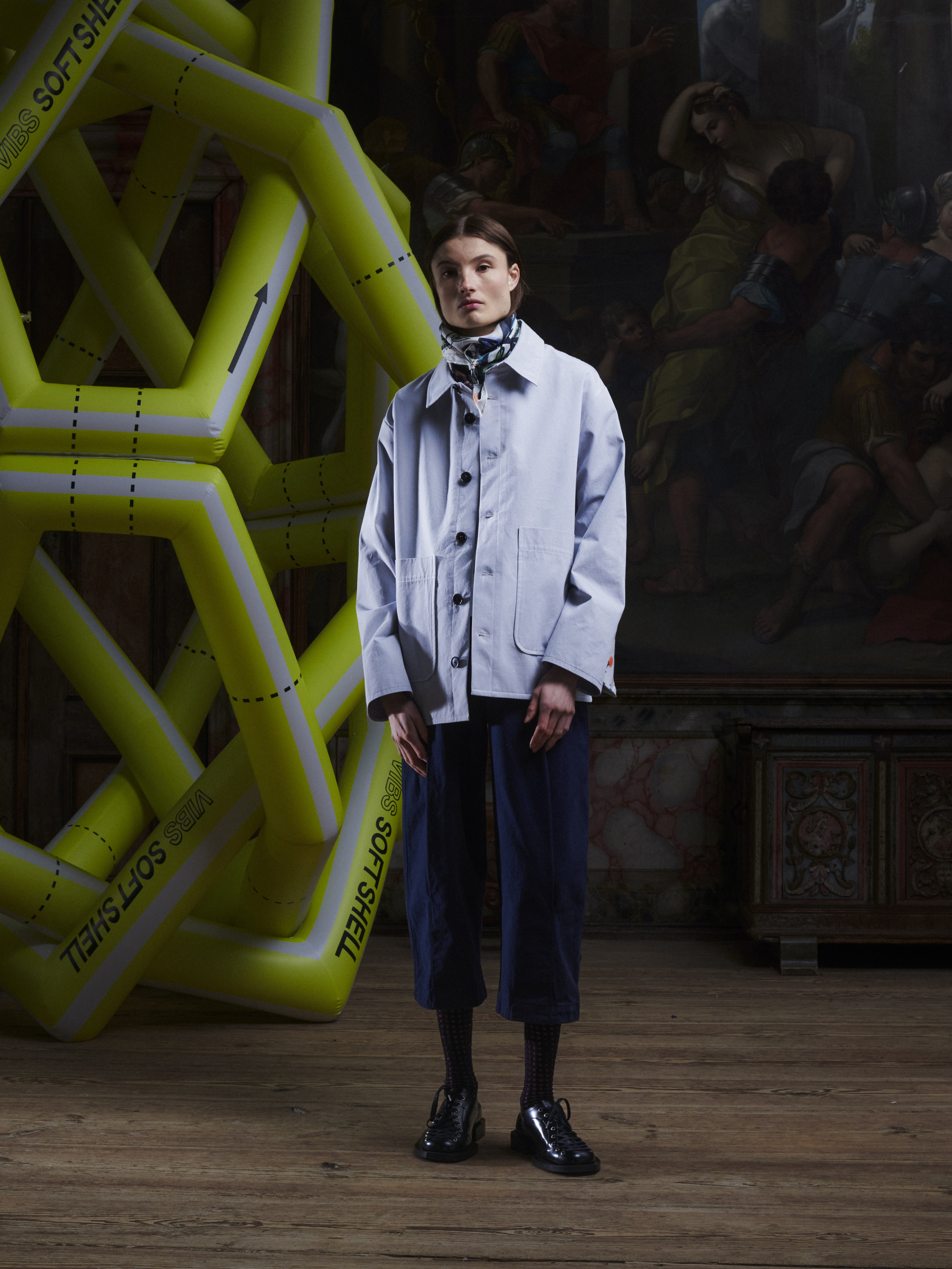 Front view of the female model wearing the Care Jacket in Carrots from Henrik Vibskov Spring/Summer 2026 Studio Collection, displaying the carrot pattern, double-breasted closure, long sleeves, and unisex silhouette.