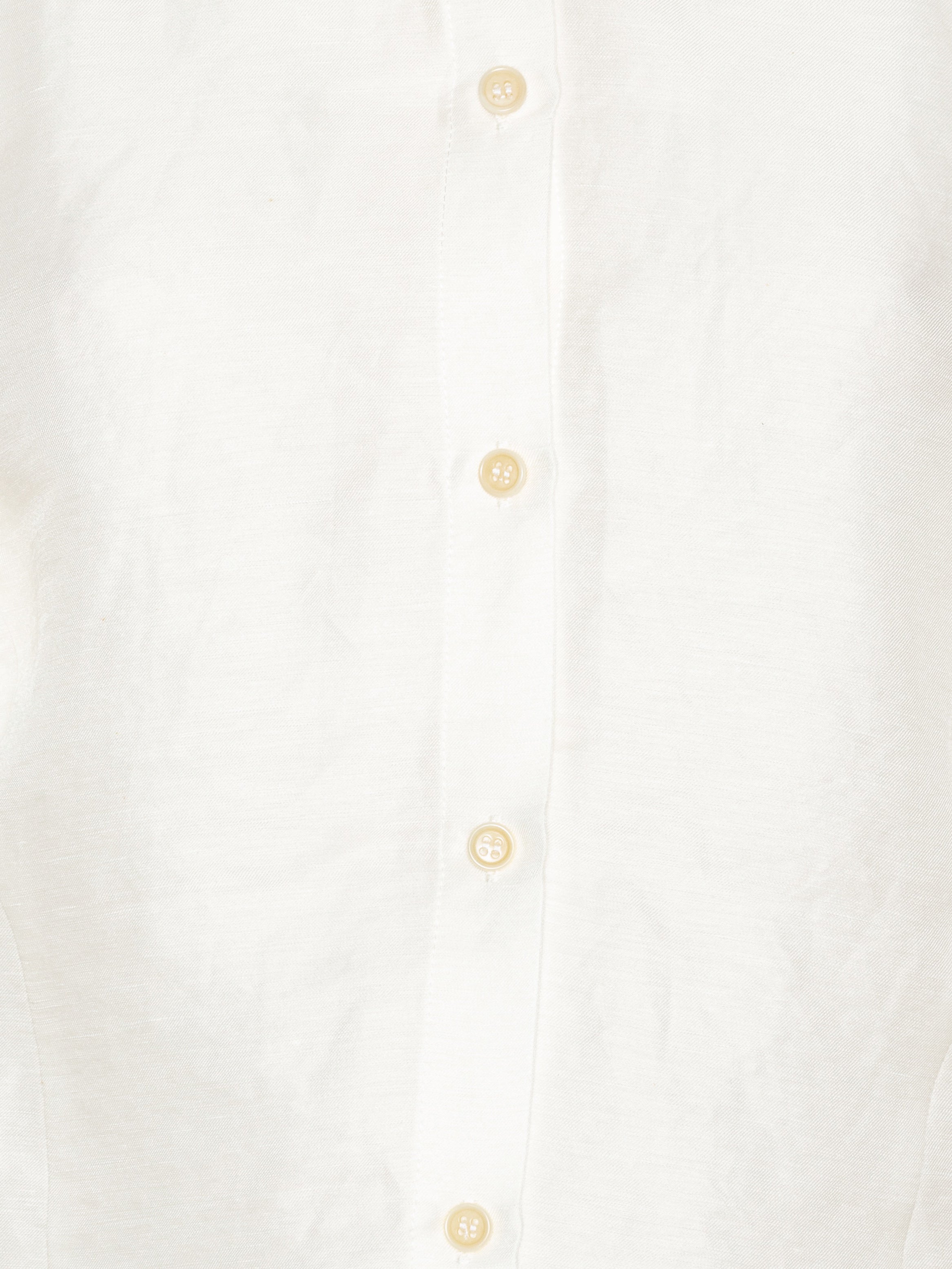 Close-up of the Case Shirt in White from Henrik Vibskov Spring/Summer 2026 Studio Collection, showing the crisp white fabric, collar detailing, button placket, and raglan sleeve seams.