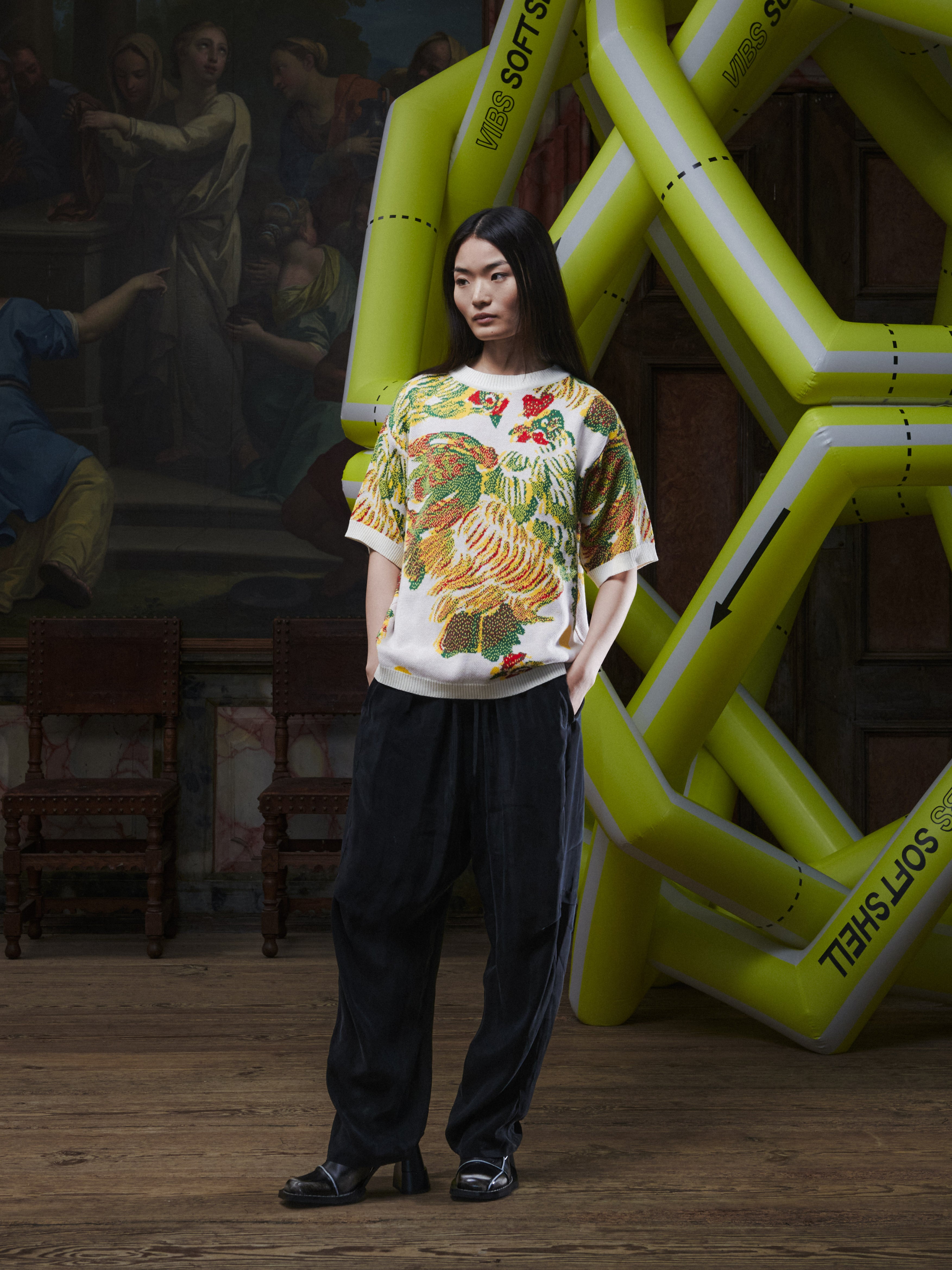 Front view of the female model wearing the Chicken T Knit in Chicken Ecru from Henrik Vibskov Spring/Summer 2026 Studio Collection, displaying the beige knit, chicken motif, crew neck, and unisex fit.