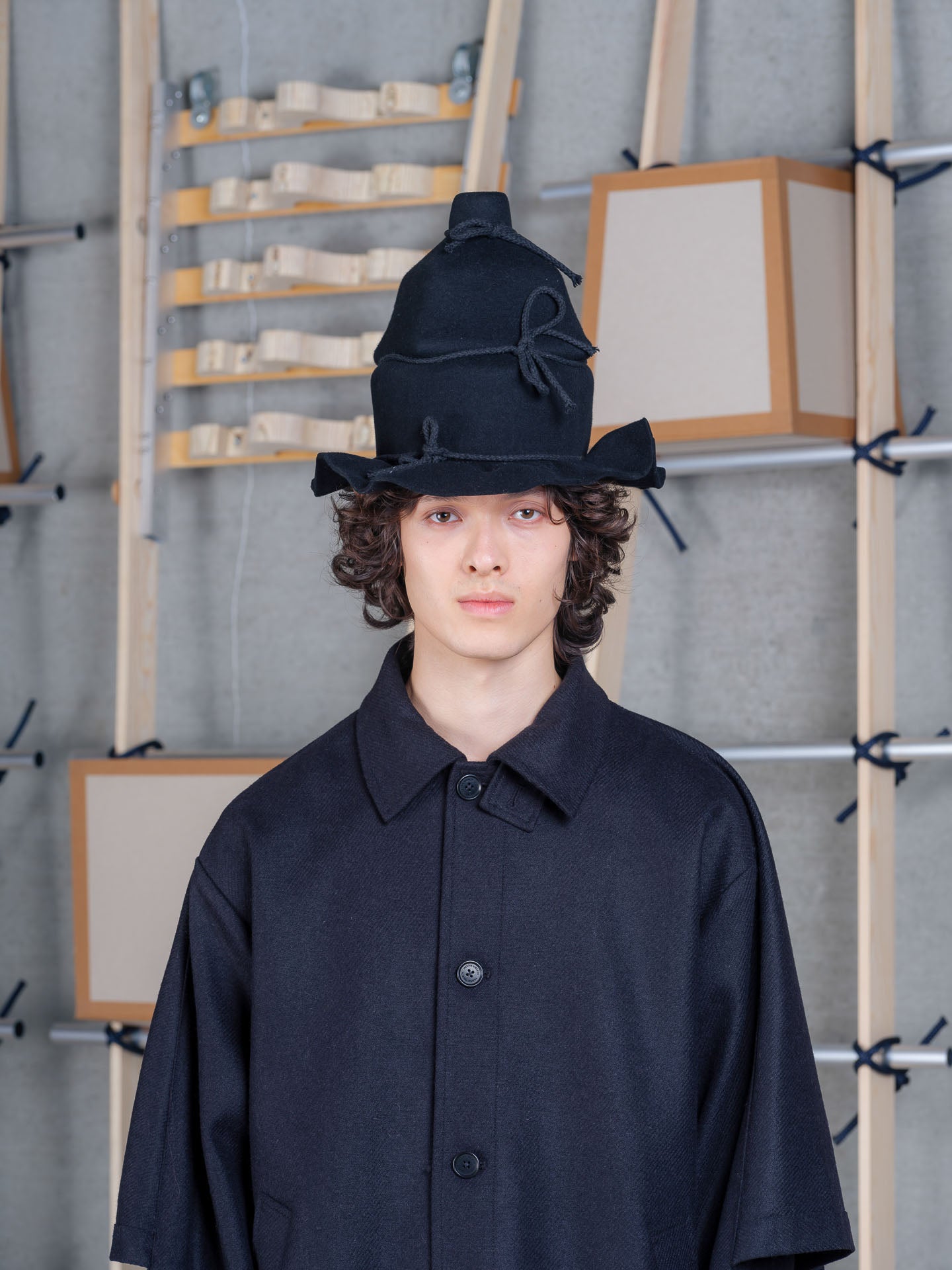 Model wearing Henrik Vibskov Christo Wrap Hat in black wool with layered crown and sculptural wrapped silhouette