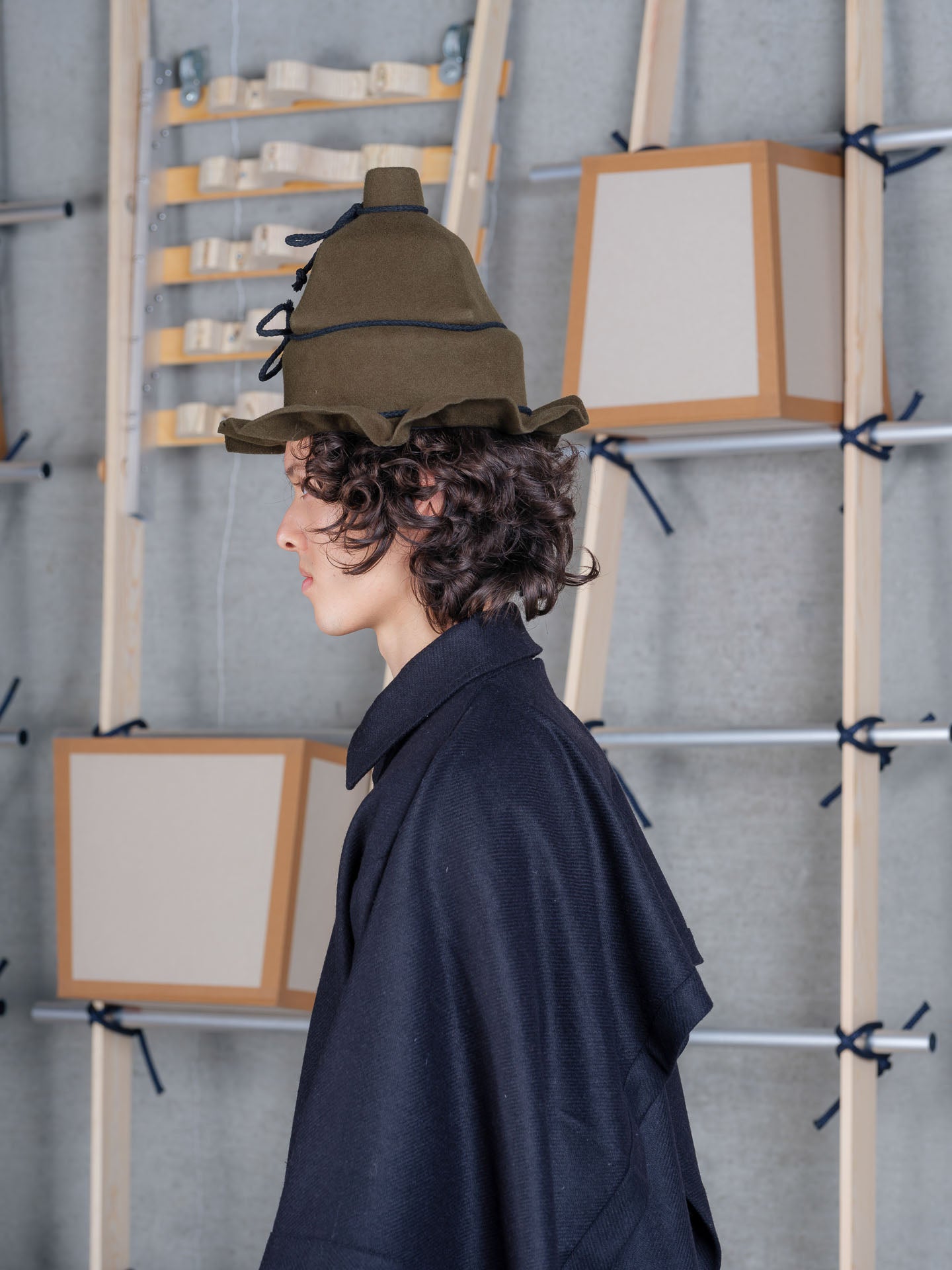 Side view of Henrik Vibskov Christo Wrap Hat in moss green showing contrast rope ties, soft wool finish and undulating brim