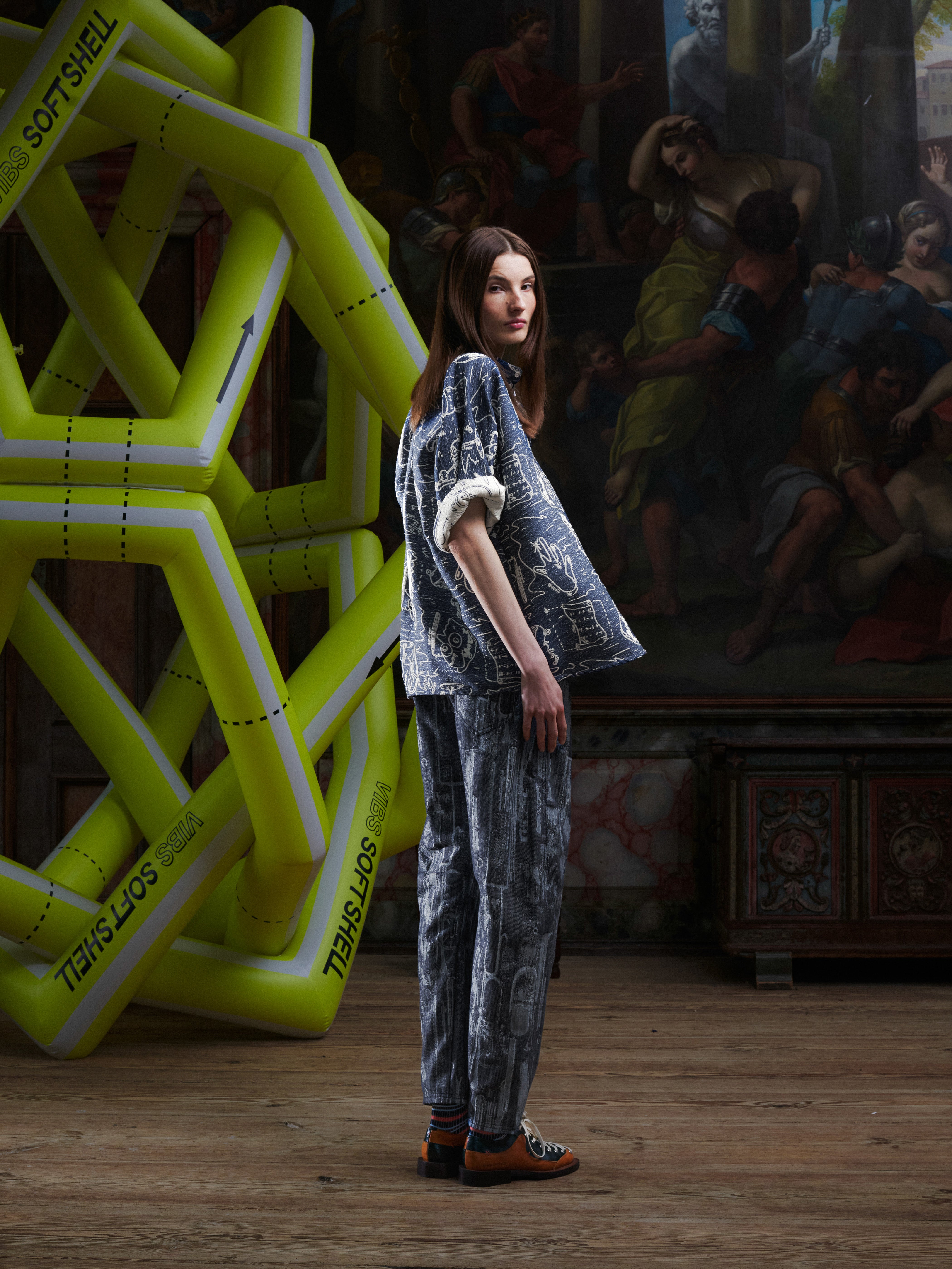 Side view of the female model wearing the Dart Polo Shirt, highlighting the loose drape, short sleeves, and doodle pattern. Model is 185cm and wears size L.