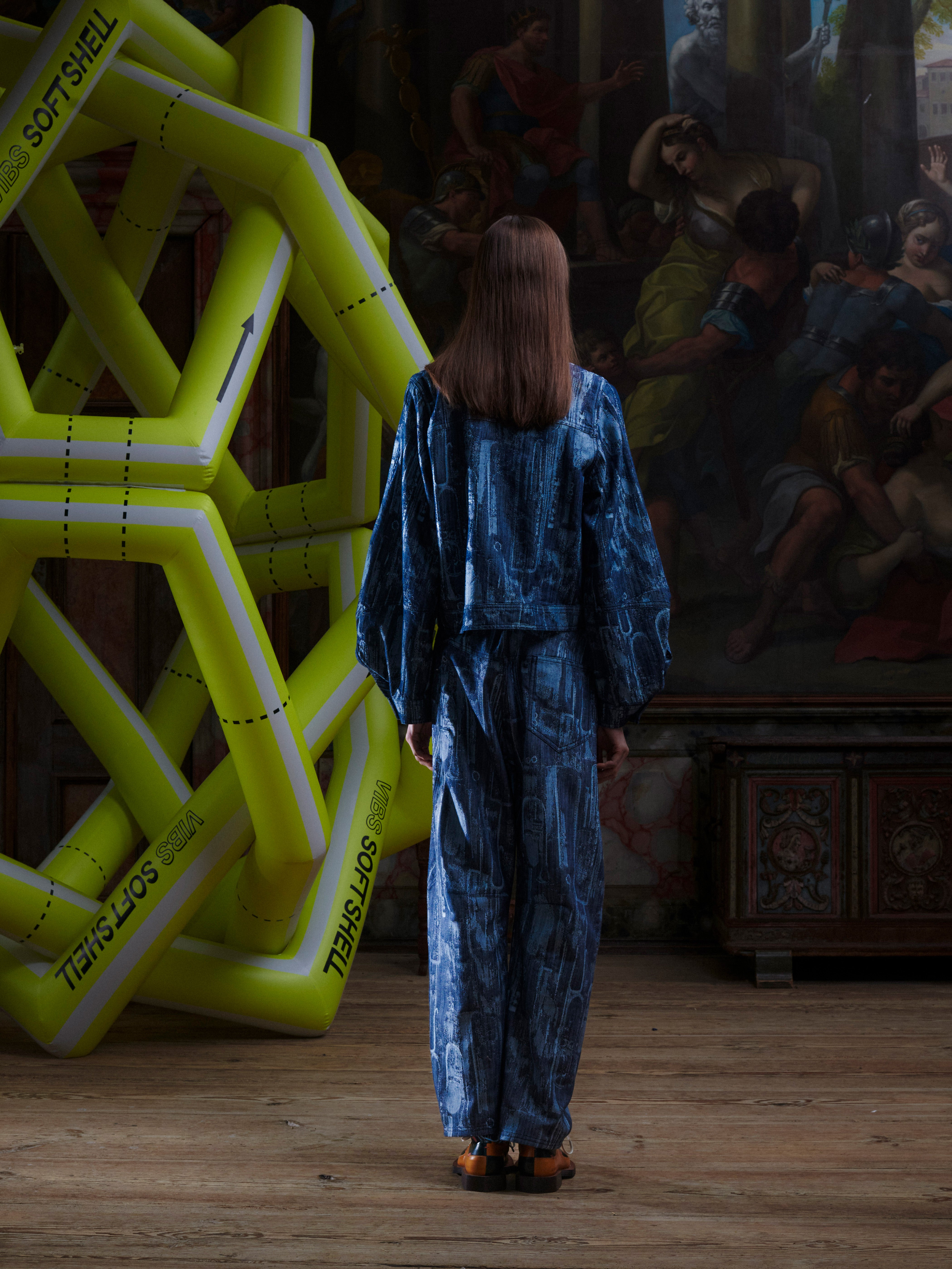 Back view of the model wearing the Dial Denim Jacket in Instrument Case, showing the abstract patterned denim and cropped shape.