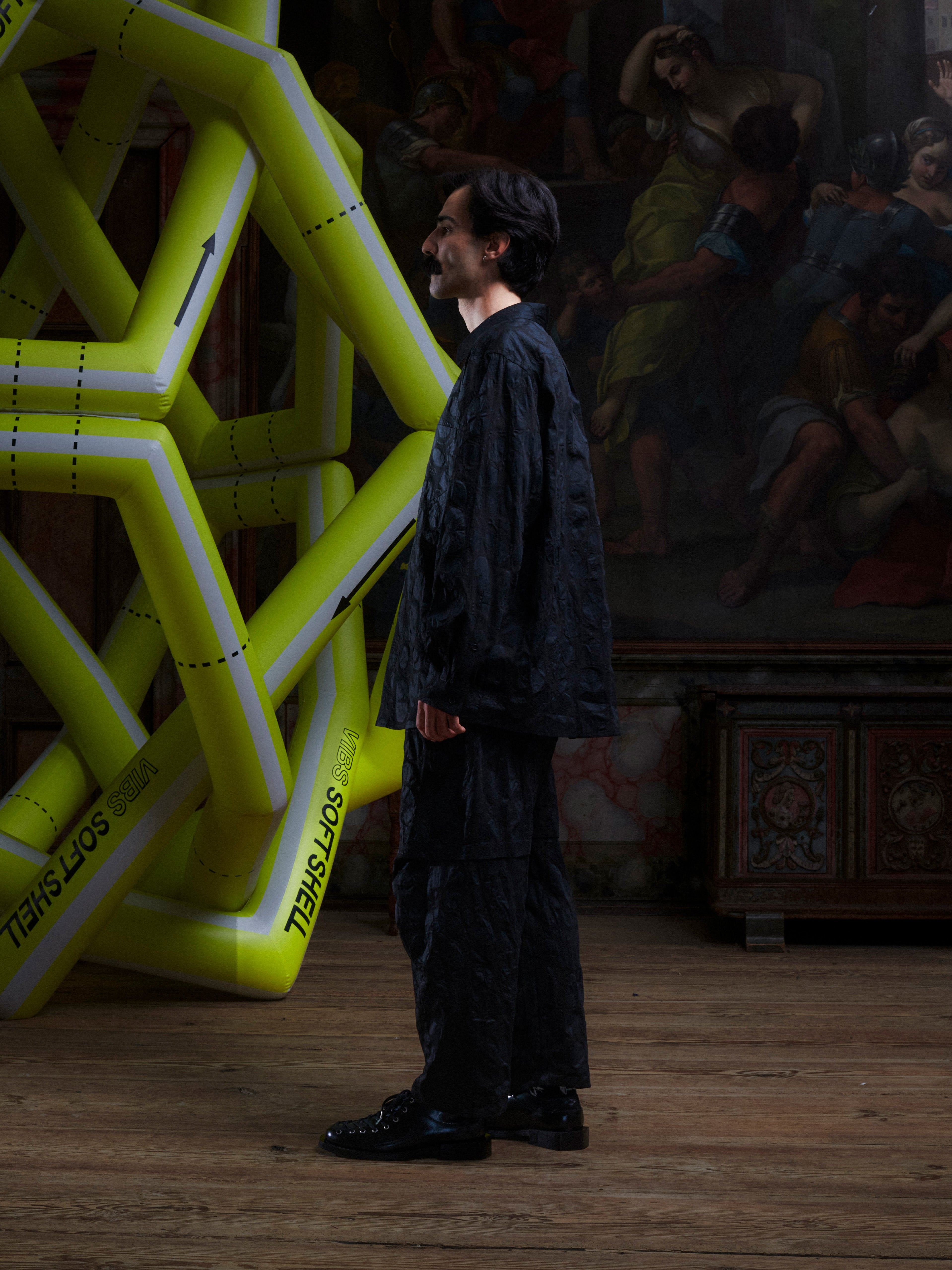 Side view of male model wearing the Drawstring Pants in Black Amulets, highlighting the straight-leg silhouette and tonal pattern.