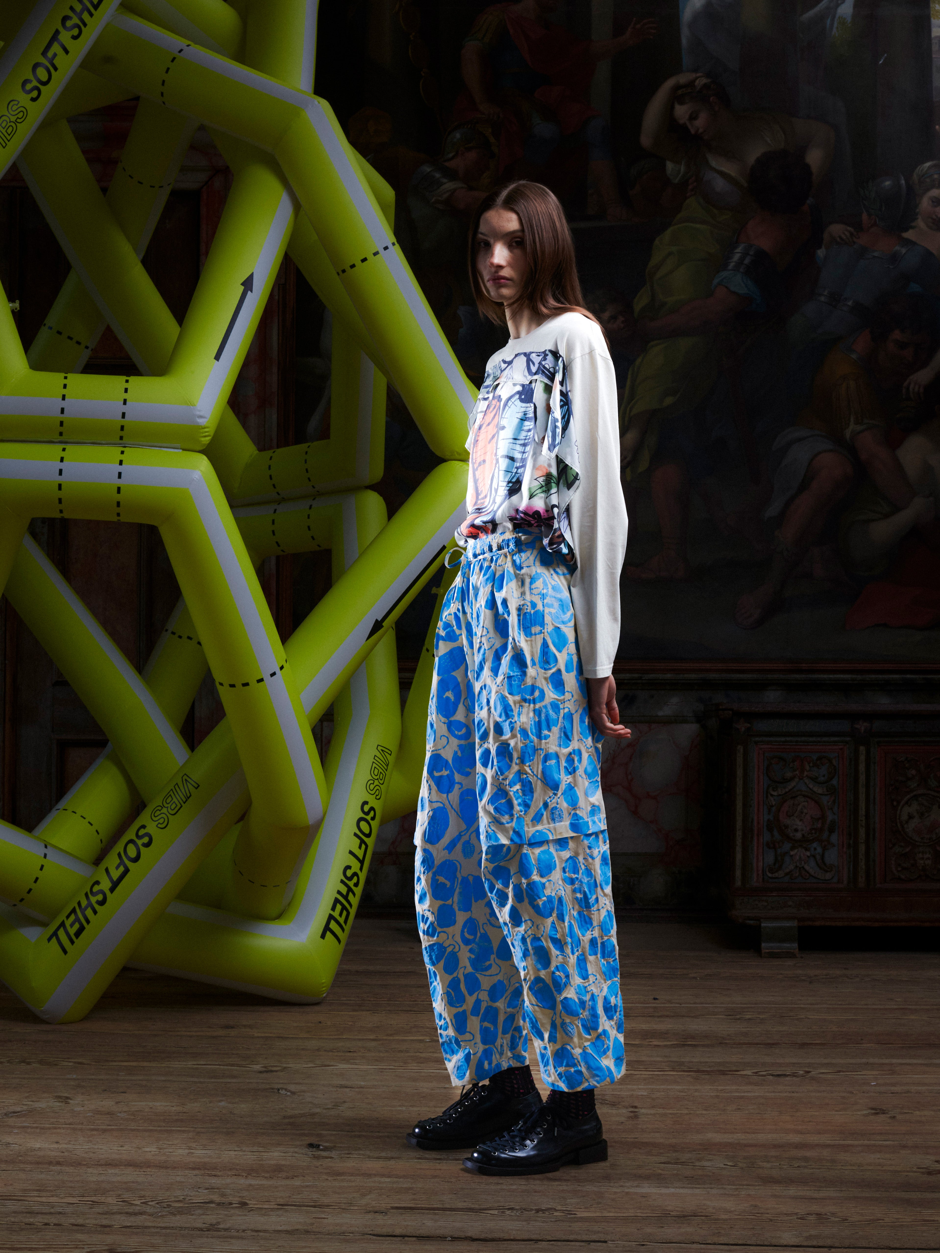Side view of female model wearing the Drawstring Pants in Ecru Amulets, highlighting the straight-leg shape, off-white fabric, and blue amulets print.