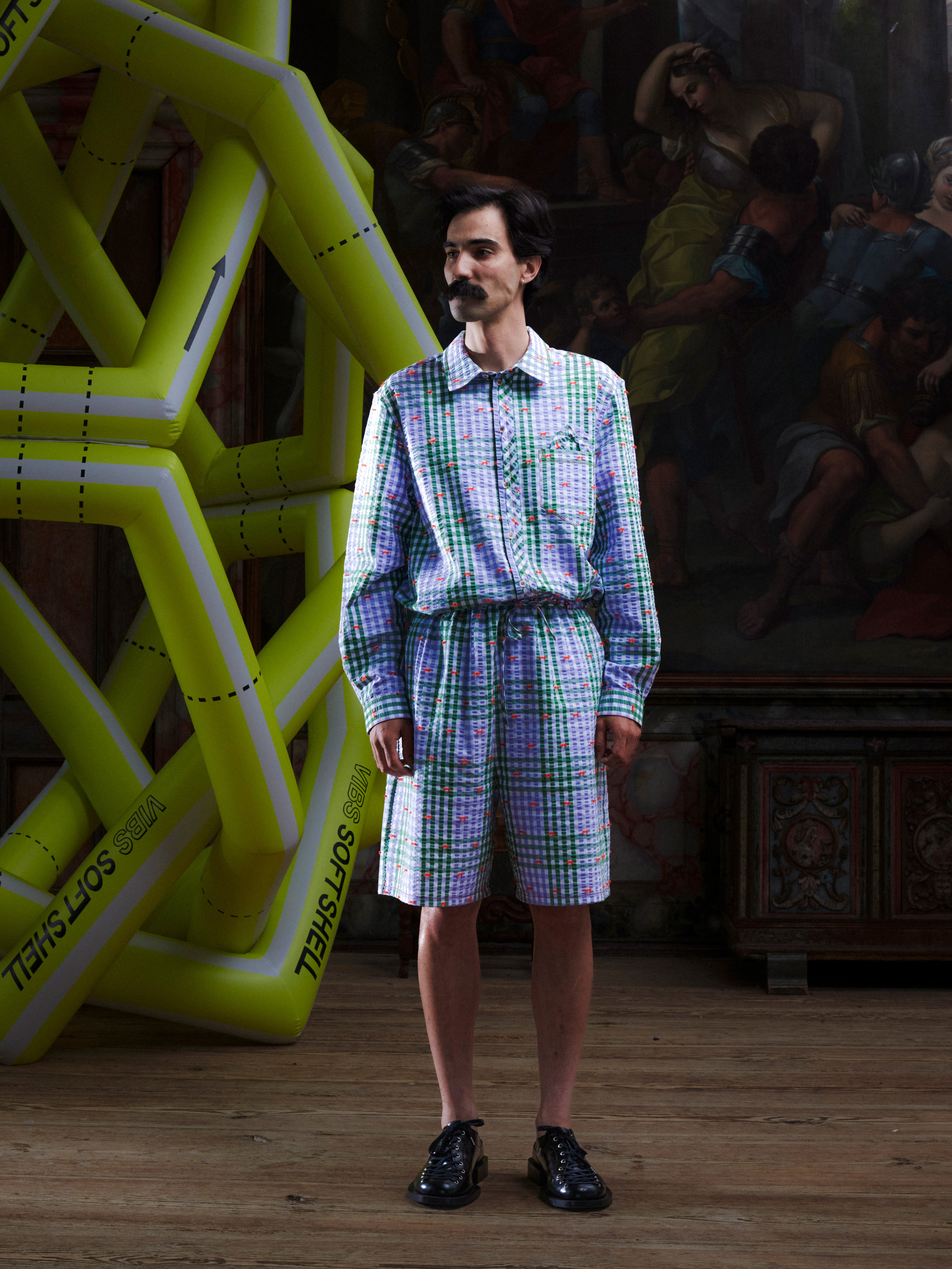 Male model wearing the Drawstring Shorts in Checks Fillé, front view. The model is 181 cm and wears size XS, showing the checked pattern, elastic waistband with drawstring, and side pockets.