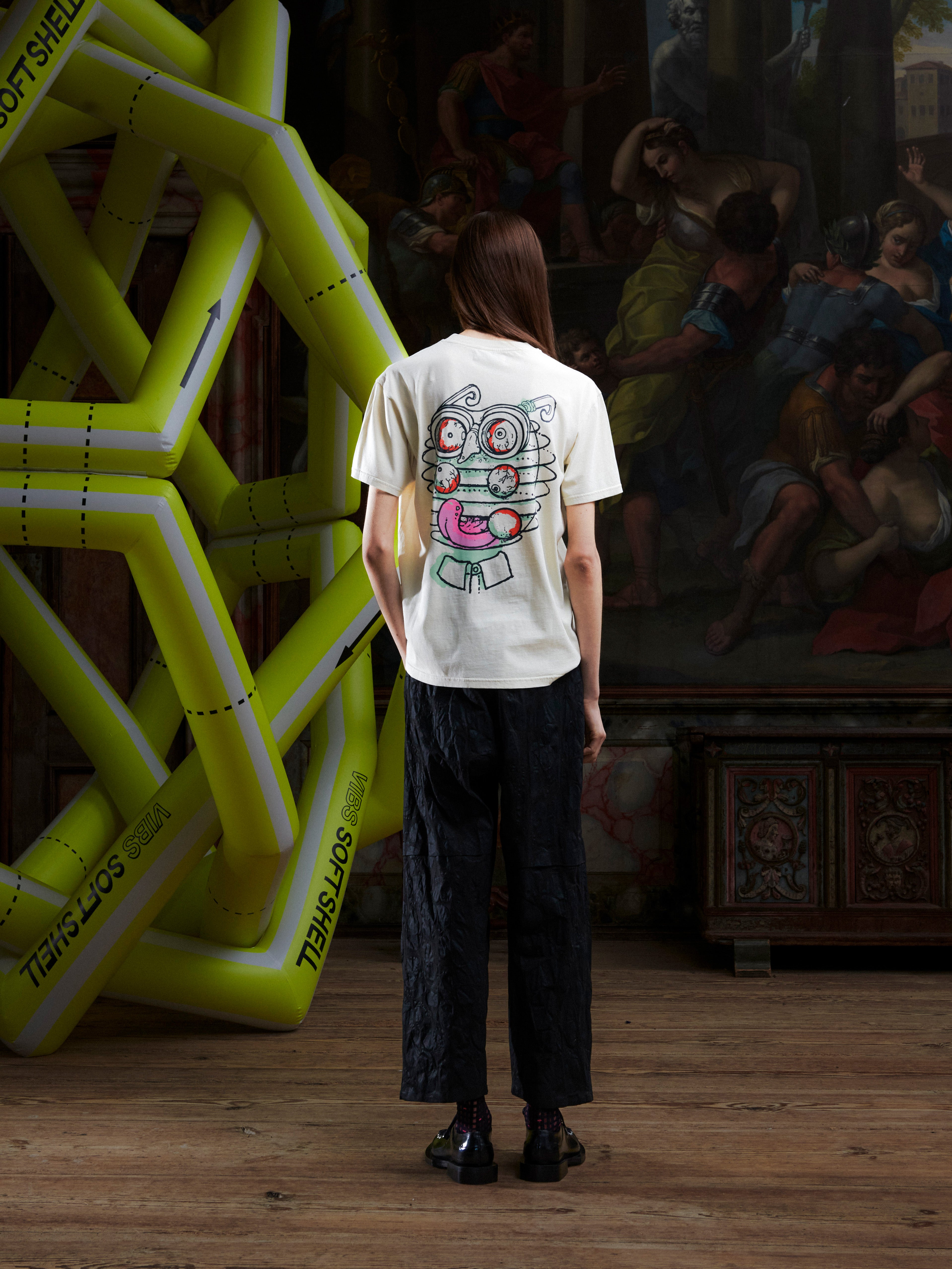 Female model wearing the Henrik Vibskov Eyeballin T in Bone White, back view, showing the plain off-white back and straight hem.