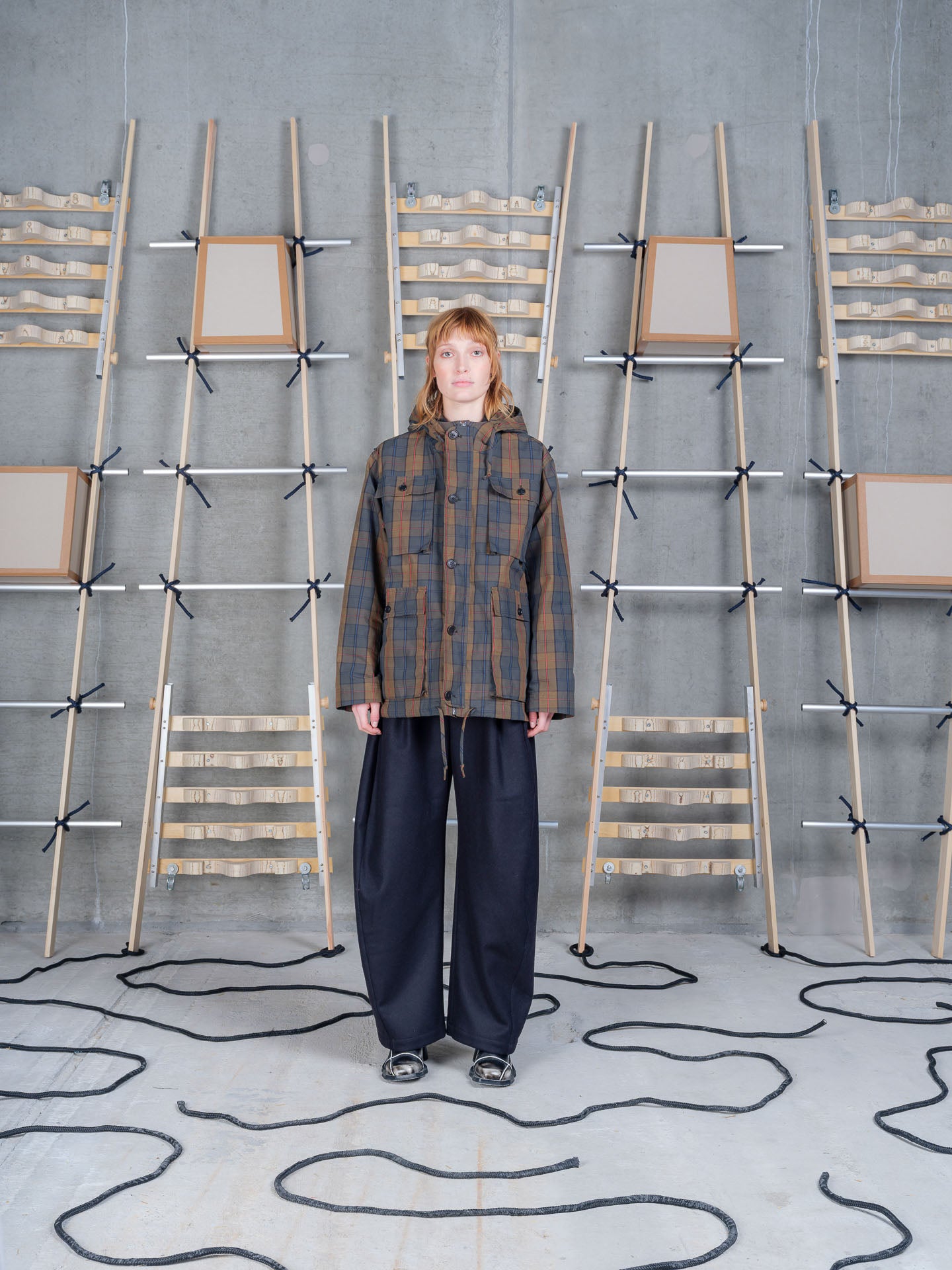 Henrik Vibskov Field Parka in Tartan worn on model, full-length front view, dry wax tartan check, drawstring hood, four-pocket utility front