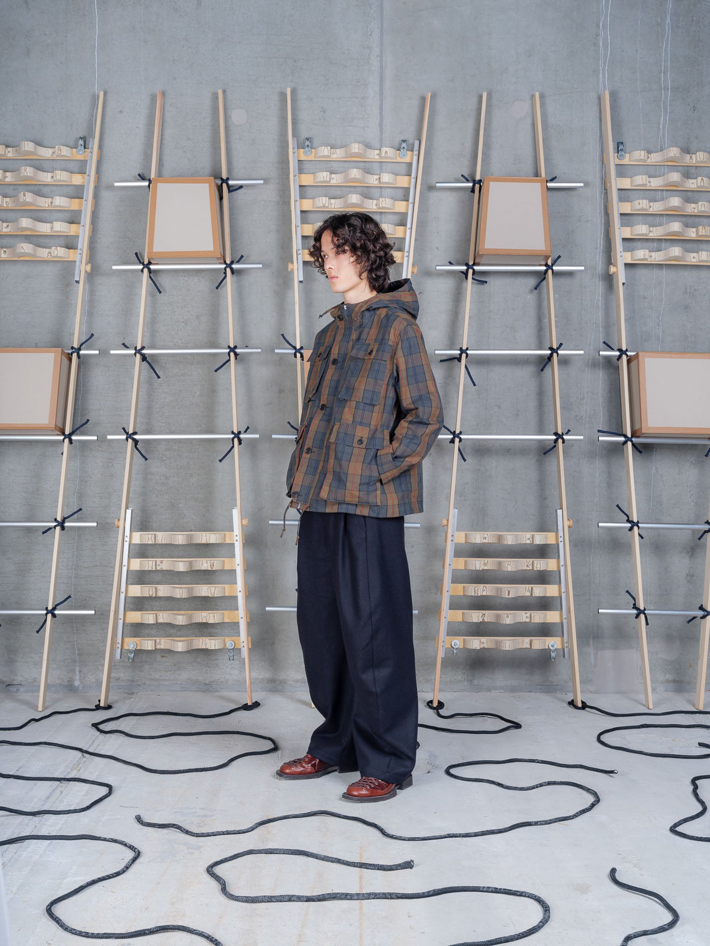 Henrik Vibskov Field Parka in Tartan worn on model, full-length front view, dry wax tartan check, drawstring hood, button-front fastening