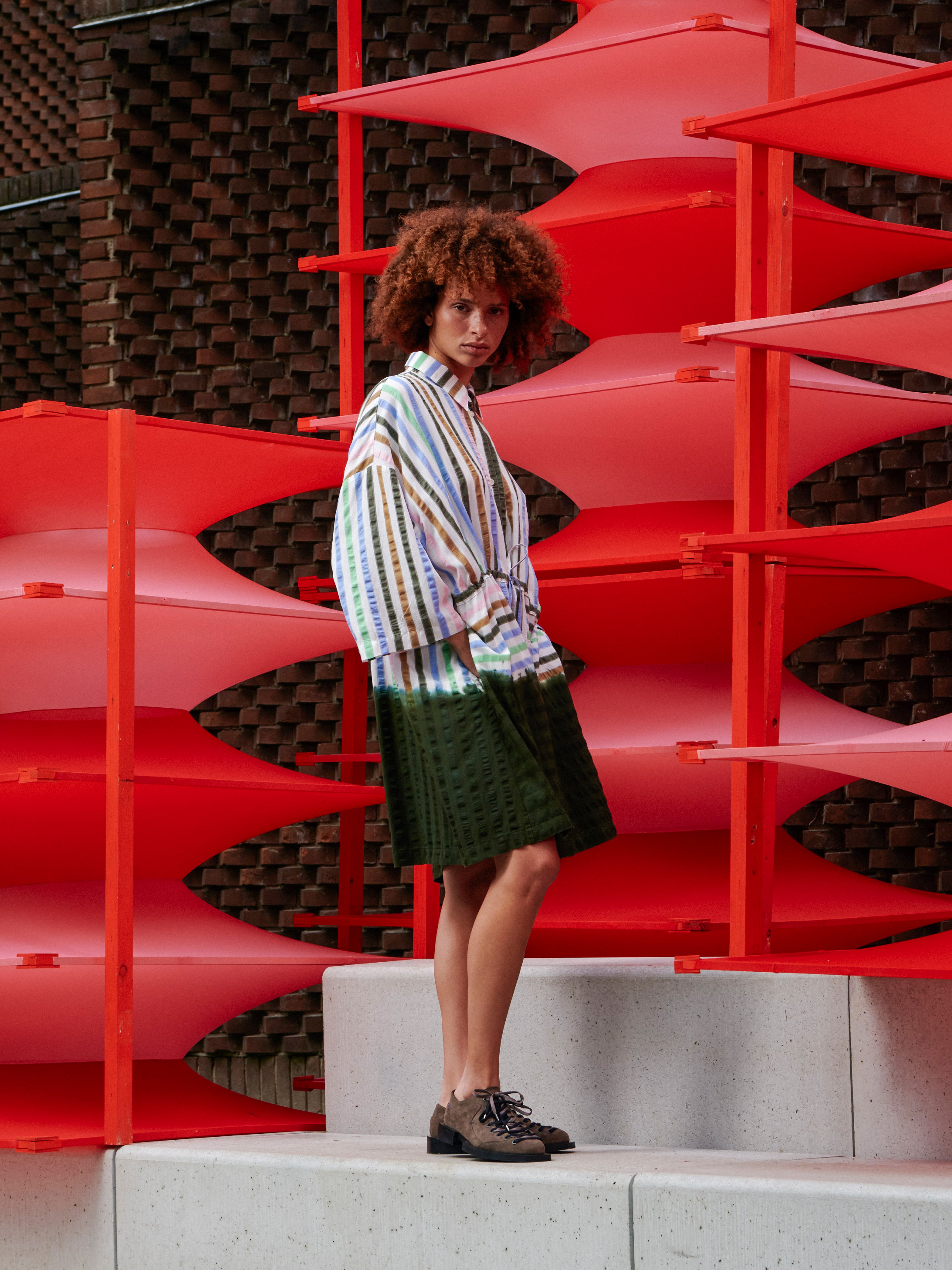 Side view of the model wearing the striped dip dye dress, highlighting the loose shape and fluid drape.