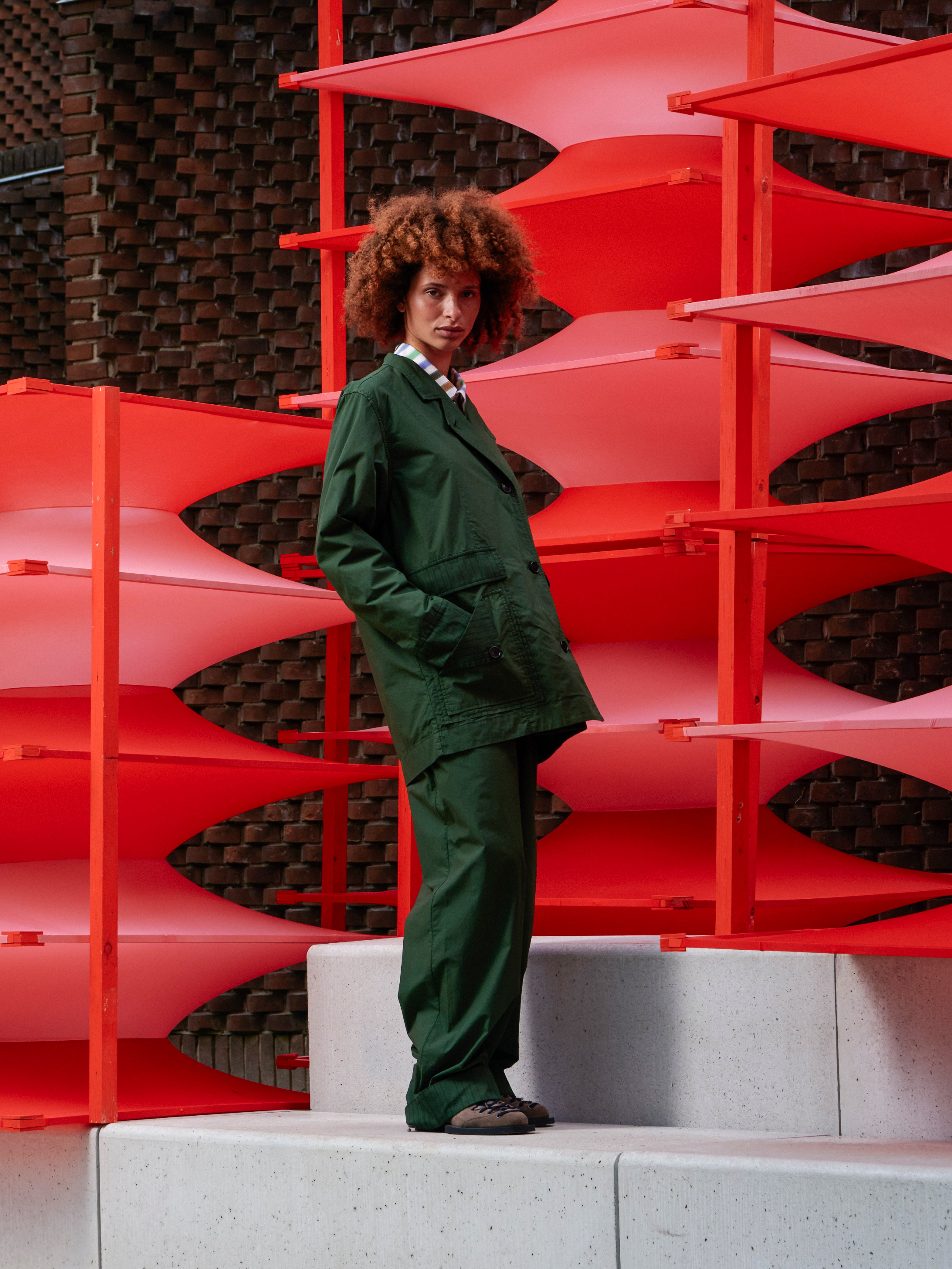 Model wearing the Mid-Air Jacket in Garden Green navy green jacket with side pockets and long sleeves, side view – Henrik Vibskov Spring/Summer 2026 Key Collection