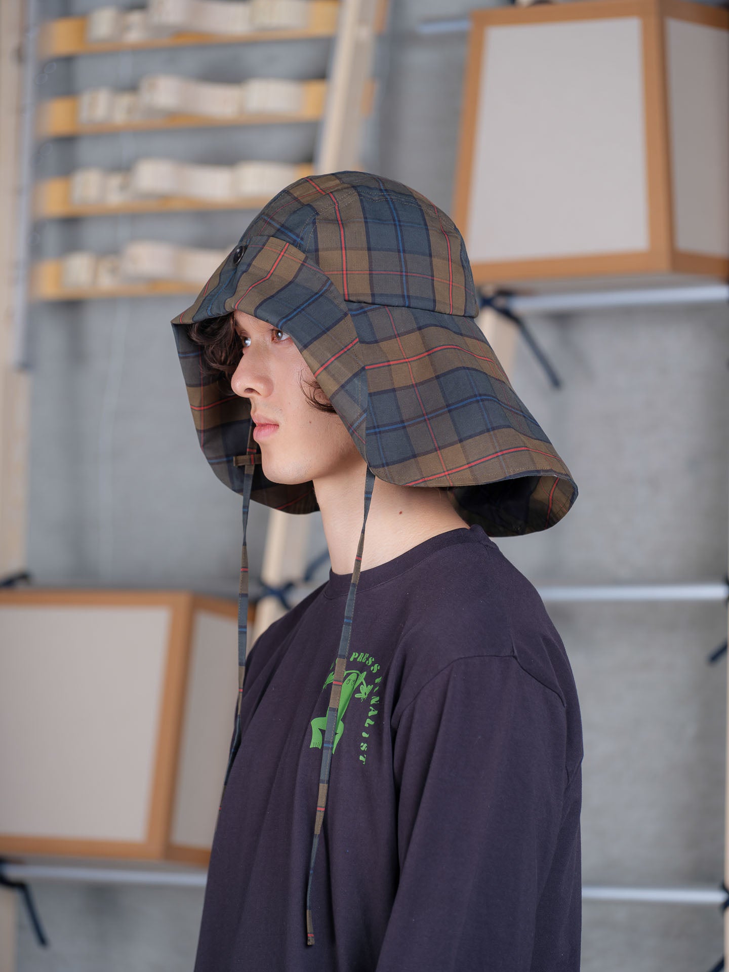 Side view of Henrik Vibskov Nilsson Fisherman Hat in tartan showing wide foldable brim and chin tie straps