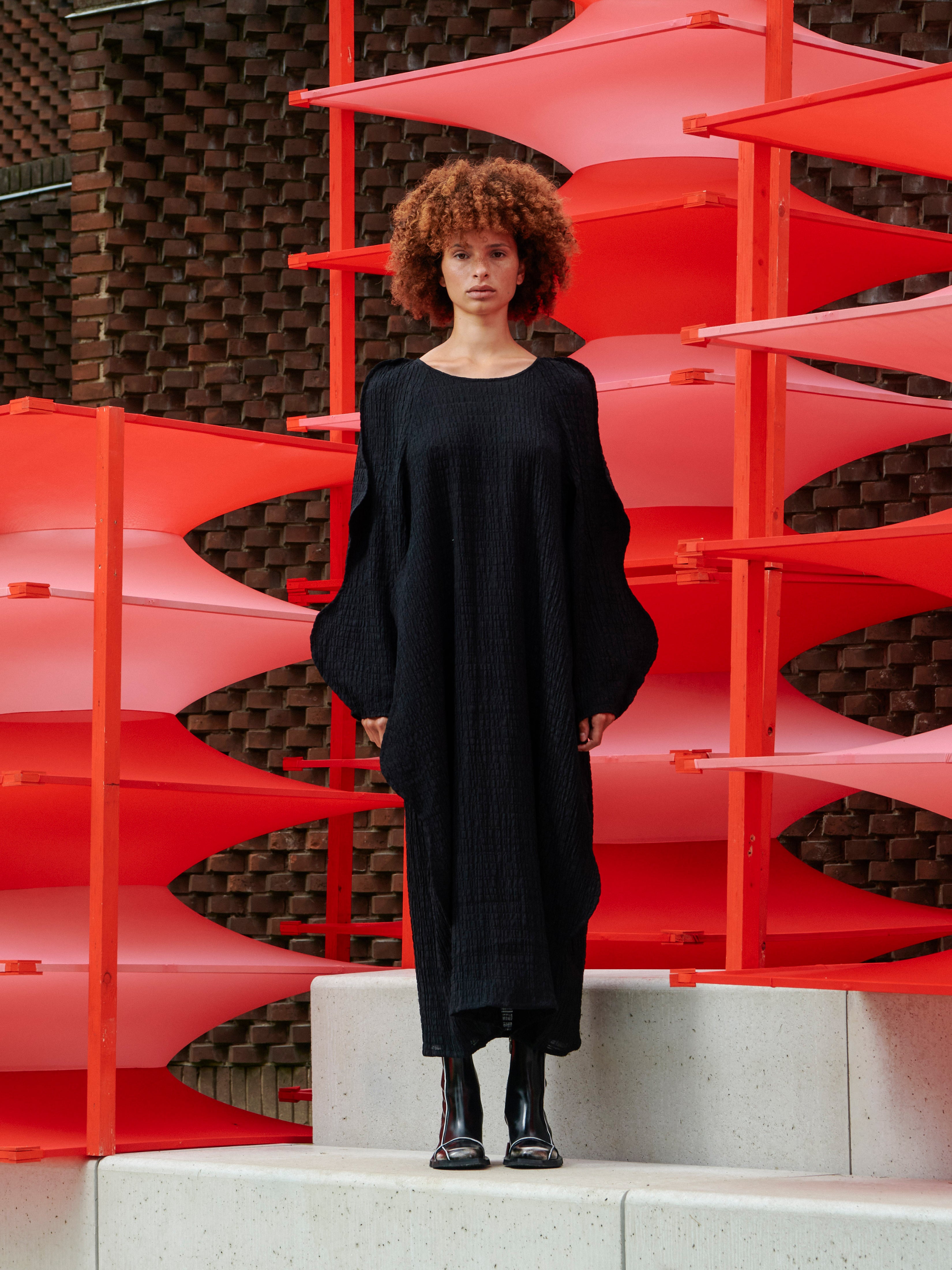 Model wearing the Octo Dress in Black black checkered textured dress with boat neck, curved long sleeves and loose fit, front view – Henrik Vibskov Spring/Summer 2026 Key Collection