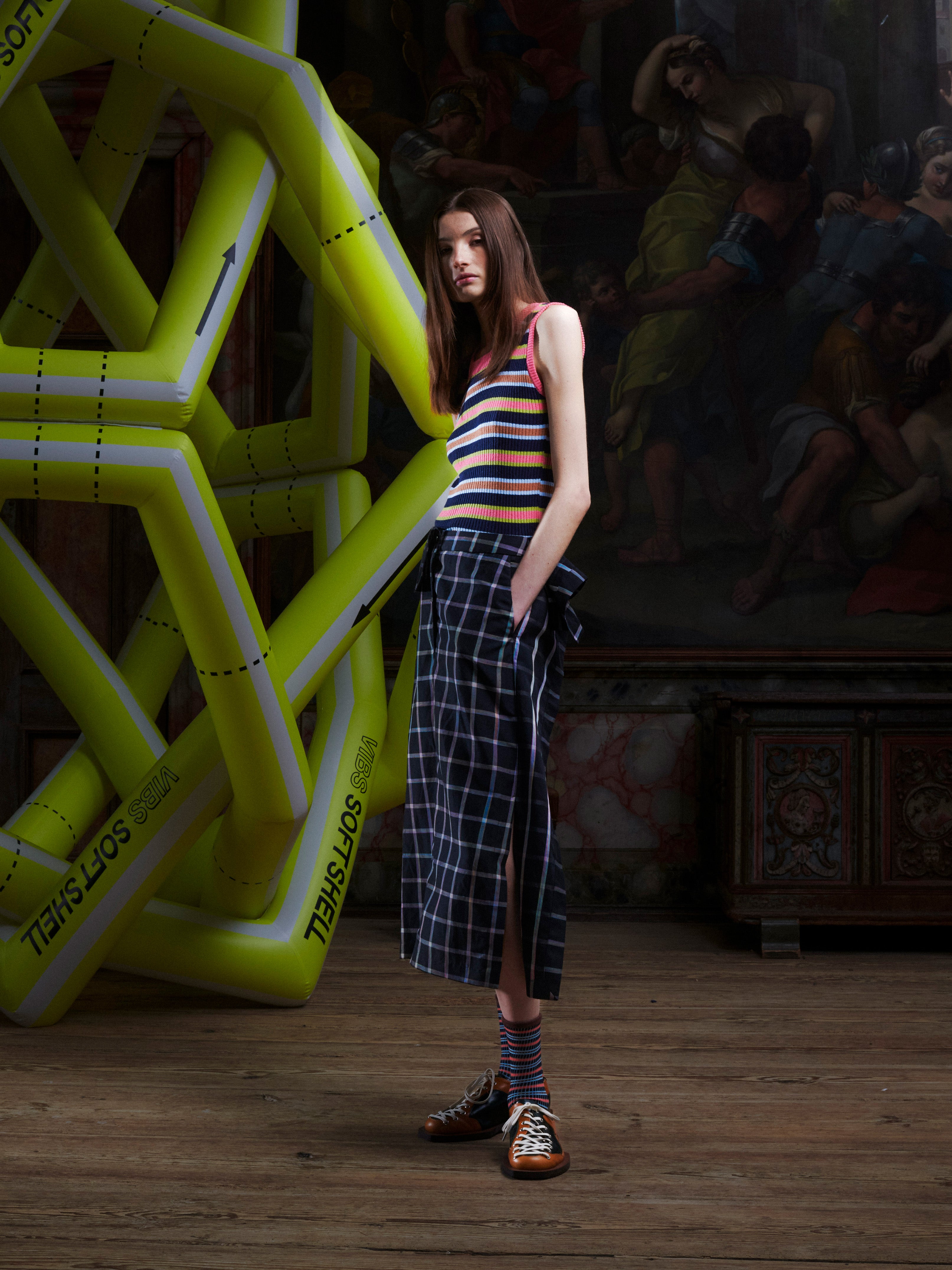 Model wearing the Henrik Vibskov Ocu Skirt in Black Checks, side view, highlighting the side slit, extra fabric detail, and straight silhouette.