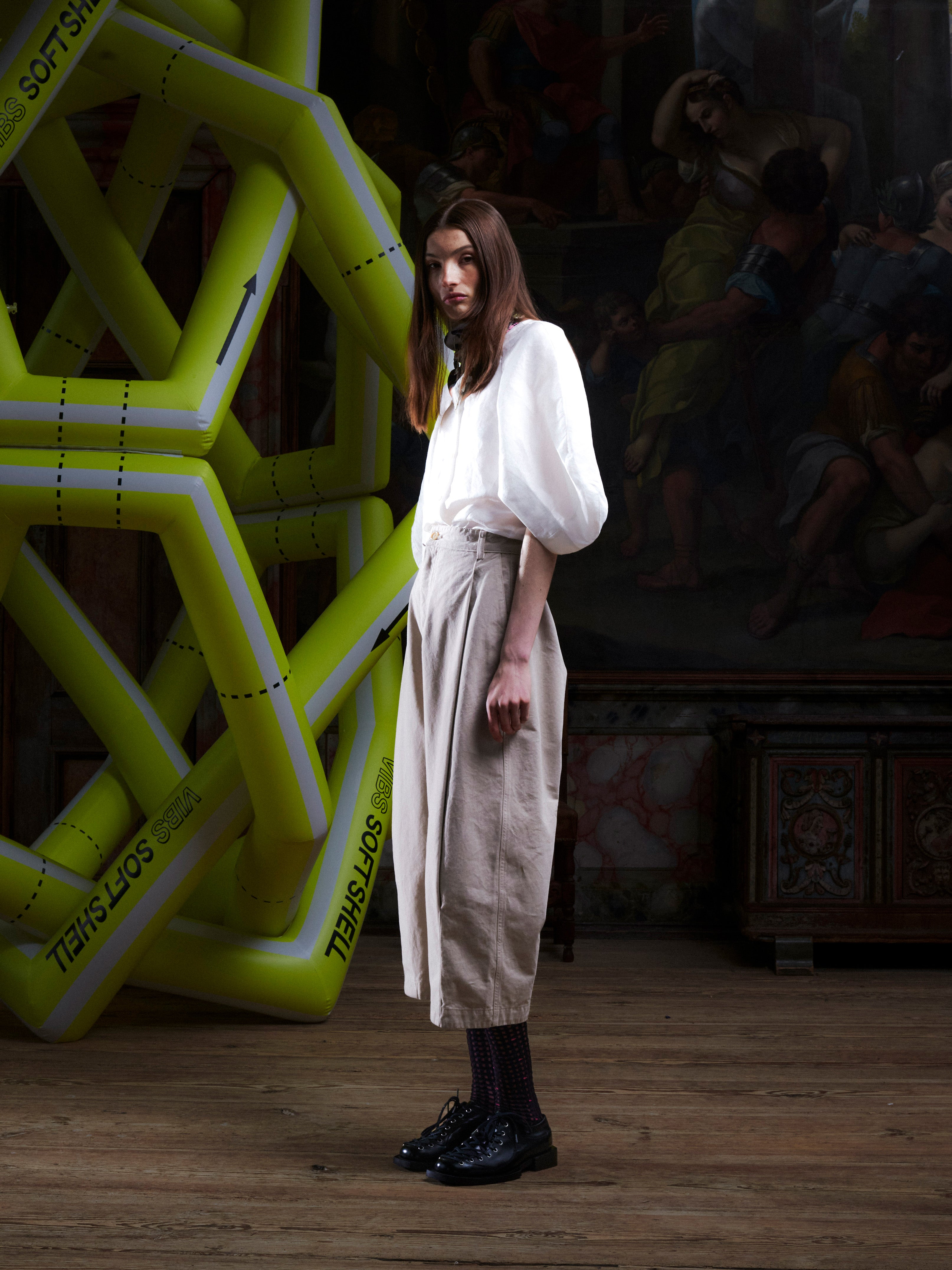 Female model wearing the Henrik Vibskov Open Dart Pants in sand beige, side view, showing the wide cropped leg, pleated front, and relaxed silhouette.