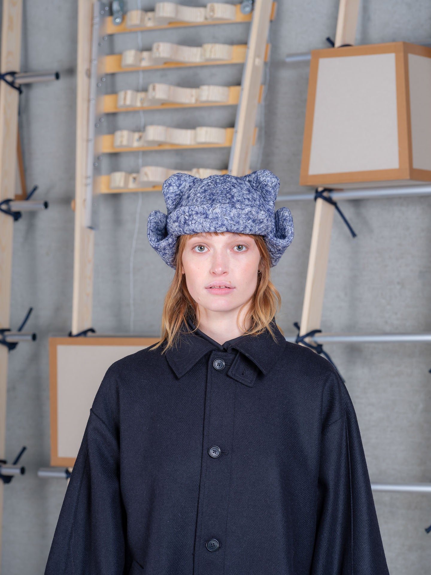 Close-up of female model wearing Henrik Vibskov Pilot Frog Hat in blue-grey organic cotton with padded ear-like details and sculptural shape