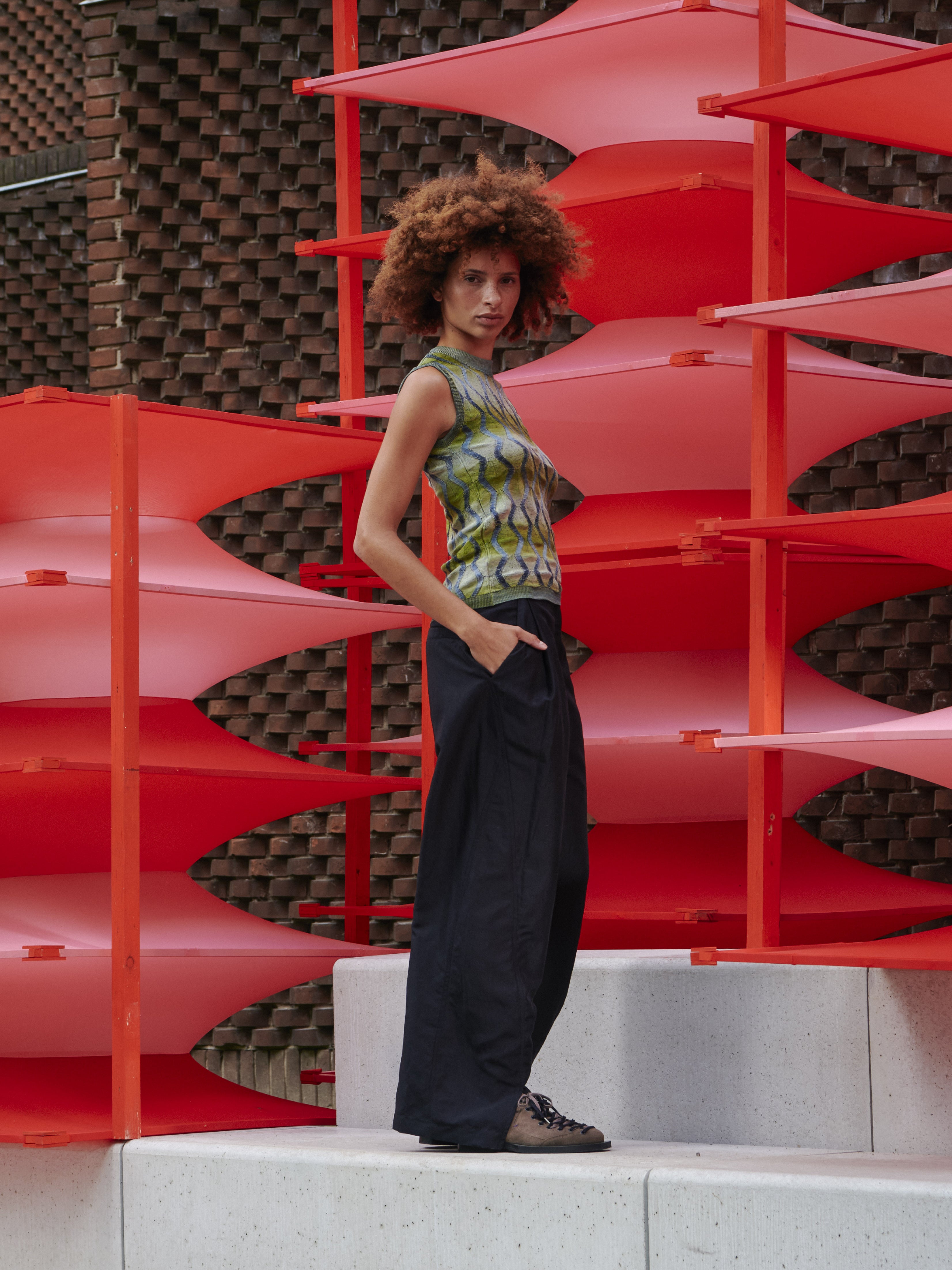 Side view of model wearing Henrik Vibskov Resonance Top in Multi Flame, showing form-fitting sleeveless silhouette, ribbed hems, and green fabric with silver pattern.