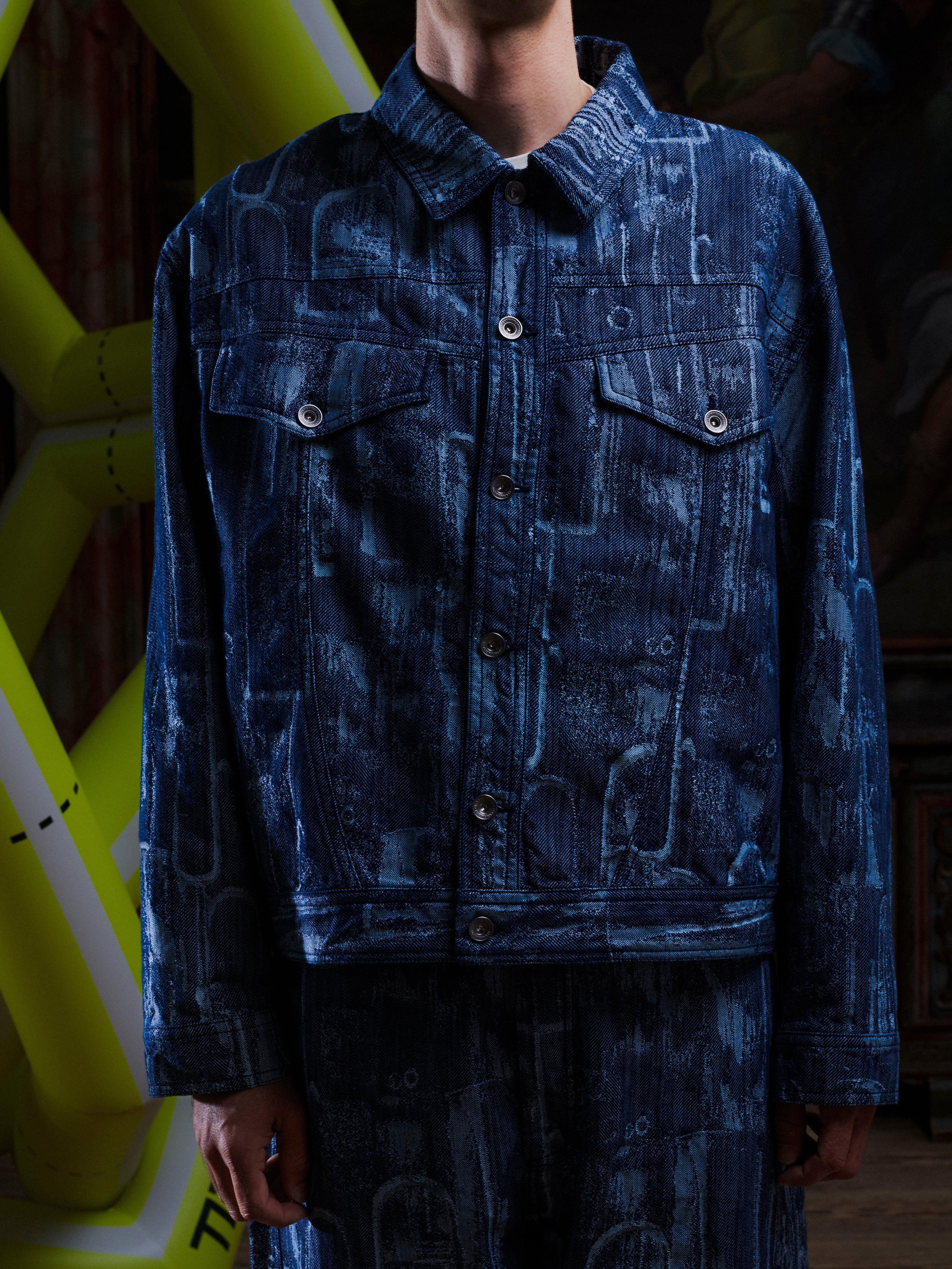 Someone wearing the grey-blue denim jacket with abstract pattern from Henrik Vibskov on a white background