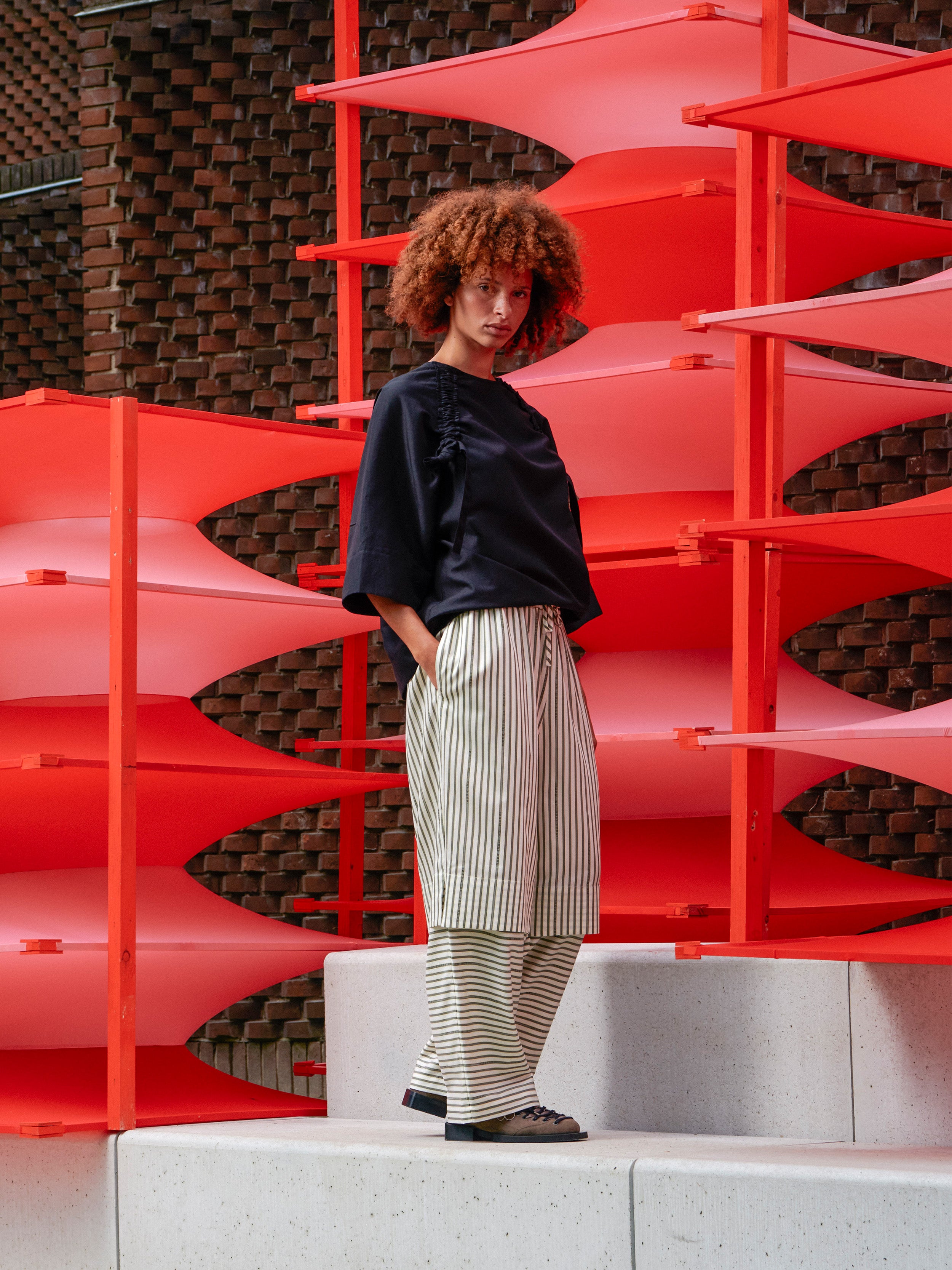 Side view of a model wearing the pants, highlighting the layered detail on the legs and sculptural wide-leg shape.