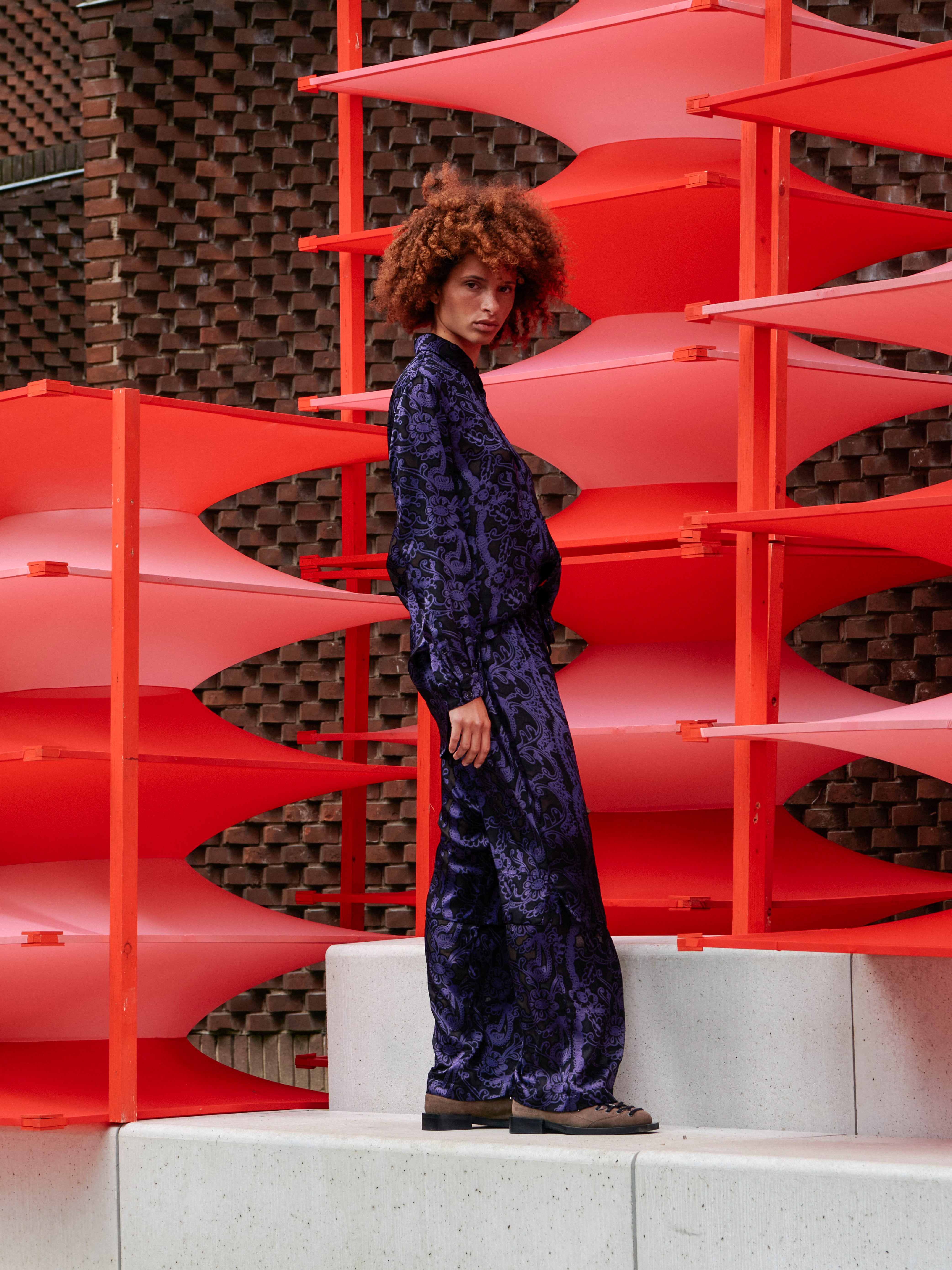Side view of the model wearing the dark purple semi-transparent Shants Pants, highlighting the layered leg structure and fluid movement.
