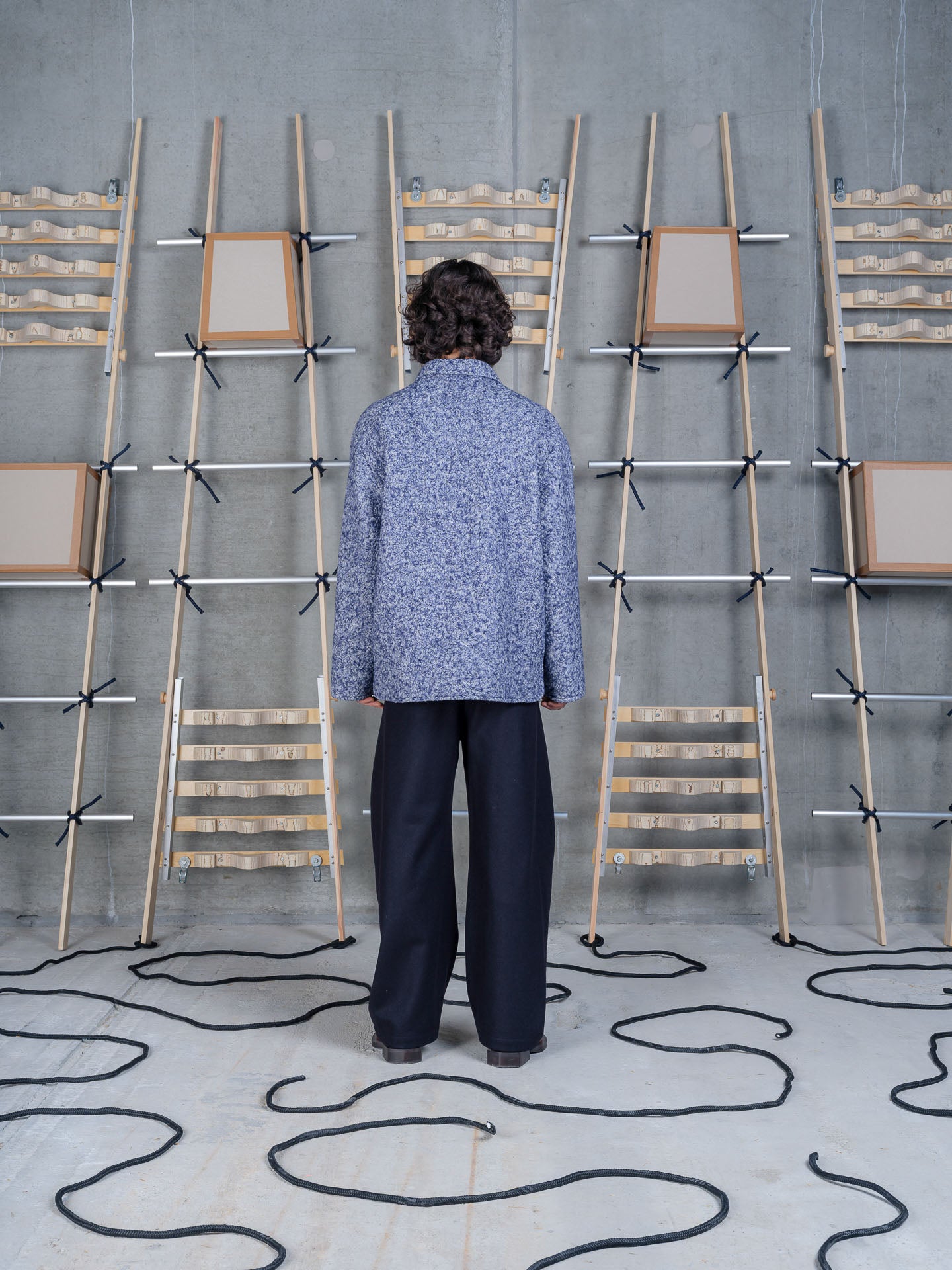 Henrik Vibskov Wheel Jacket in Blue Pebbles on-model back view, mottled bouclé texture, relaxed fit, navy trousers styling
