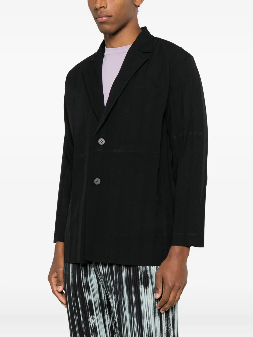 Side view of the black blazer with large plissé from Homme Plissé Issey Miyake on a white background.