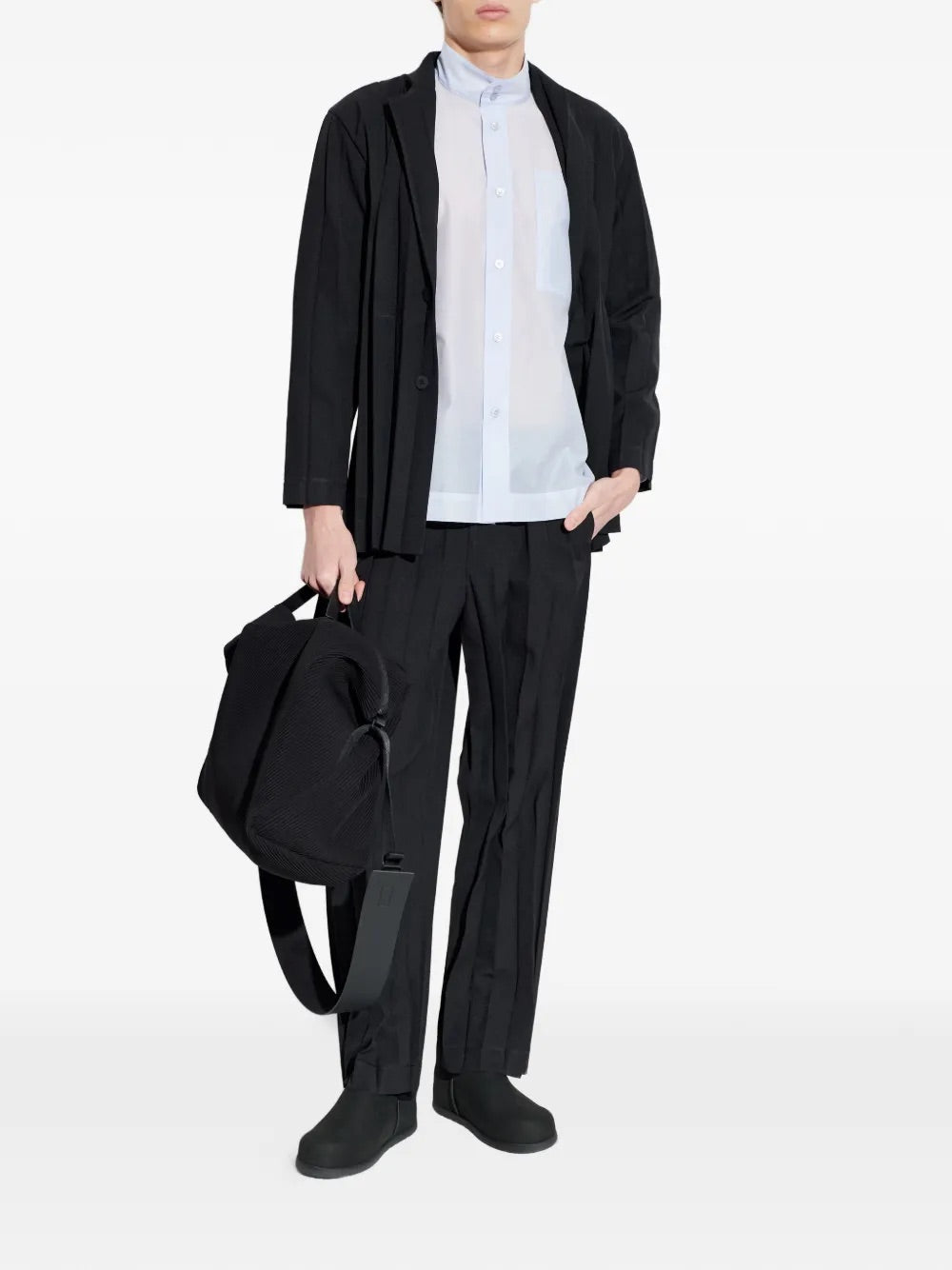 Model wearing Edge Ensemble Pants in Black by Homme Plissé Issey Miyake, full-length front view of slim-leg black plissé trousers with belt loops and side slit pockets