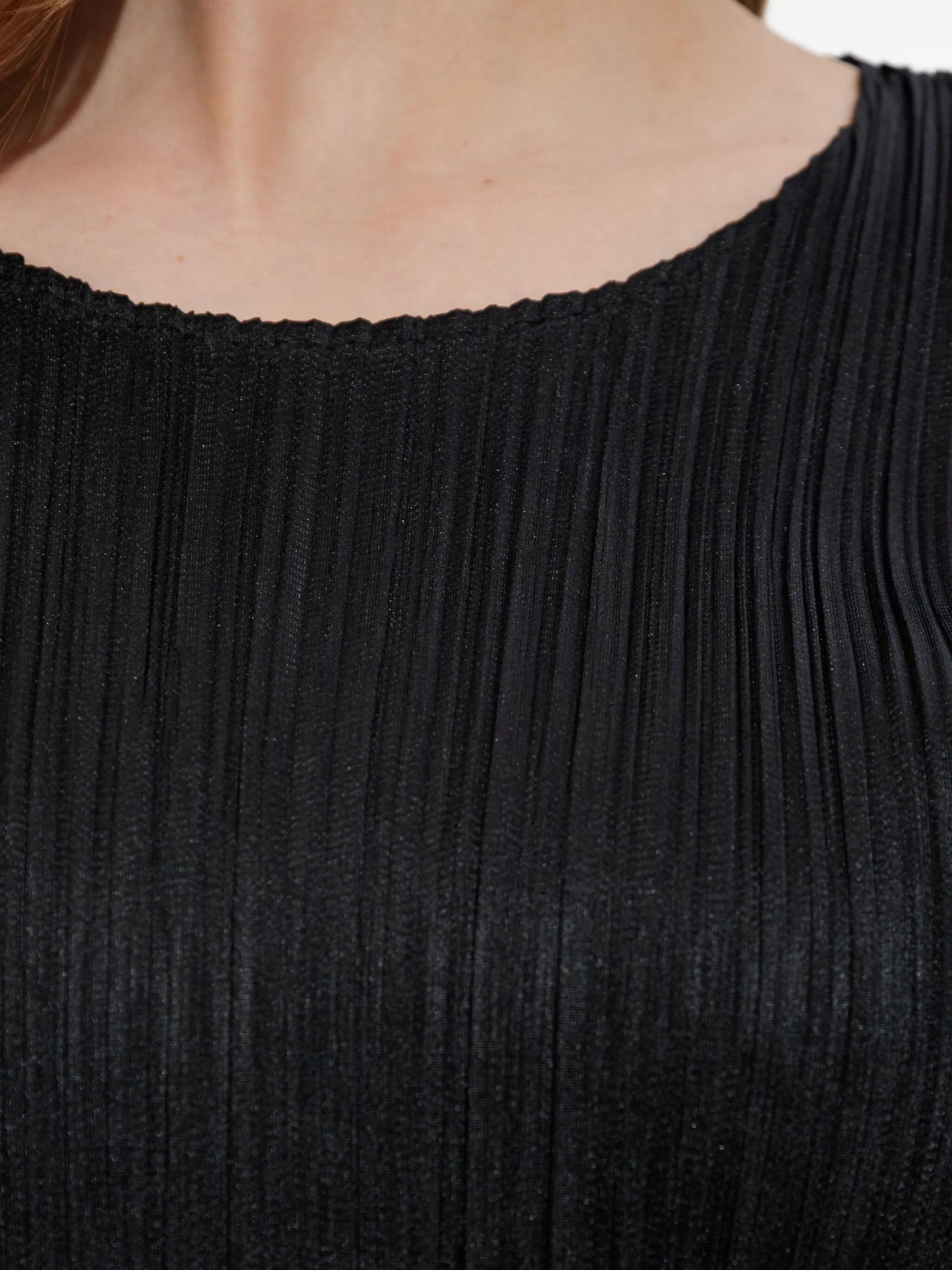 Close-up of a black pleated top with a blurred background