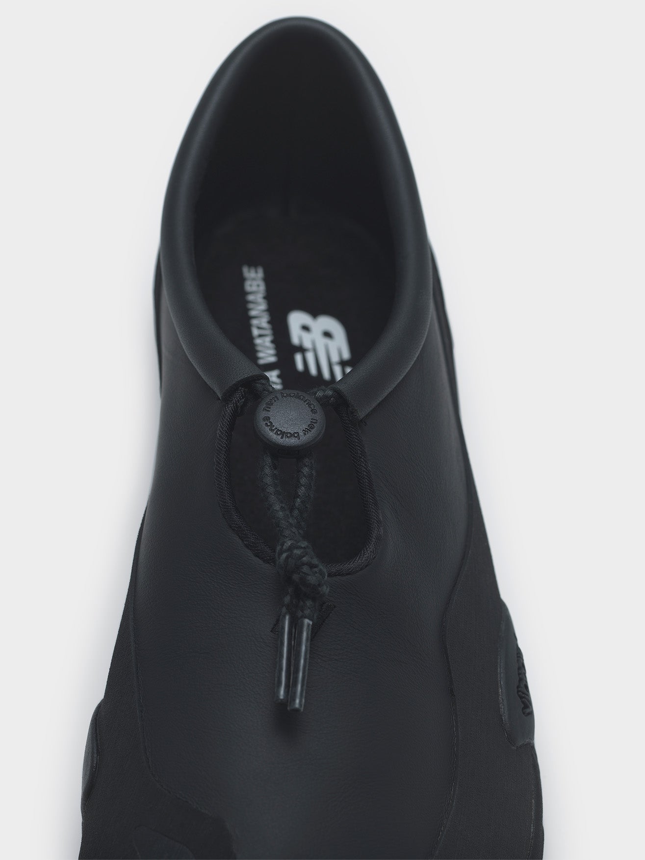 Junya Watanabe x New Balance MT10T sneakers in black, top-down close-up of toggle lace closure and dual-branded insole
