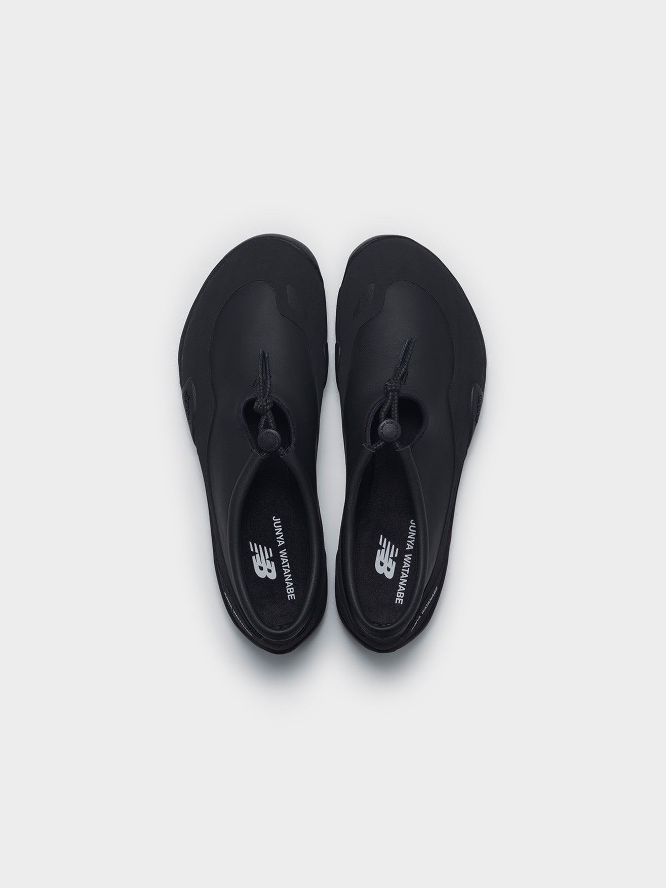 Junya Watanabe x New Balance MT10T sneakers in black, top-down view of pair, oblique toe box and dual-branded insoles