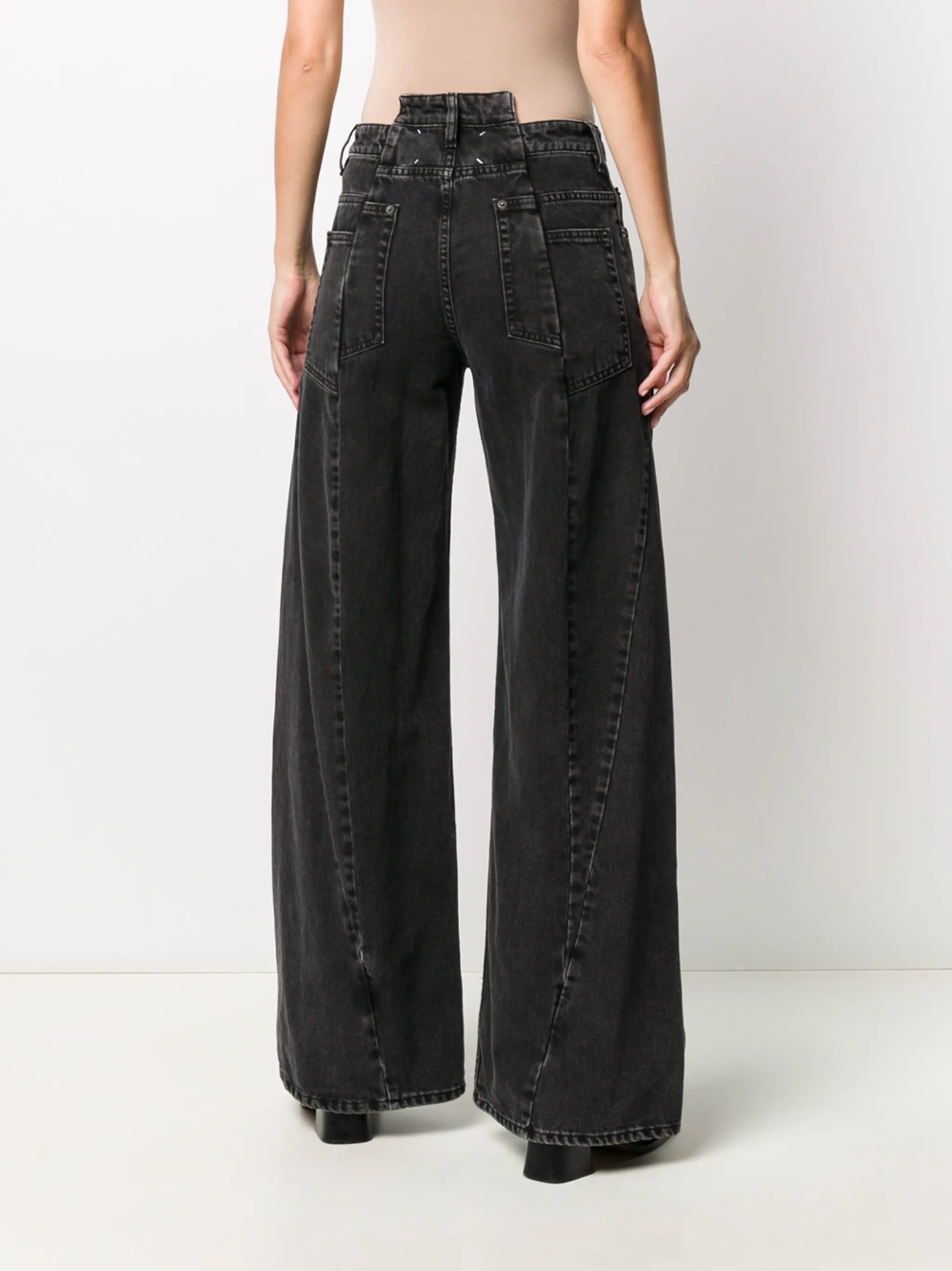 Back view of the model wearing the Medium Black Stone Maison Margiela five-pocket pants, showing the classic back pockets, washed denim finish, and the four white signature stitches.