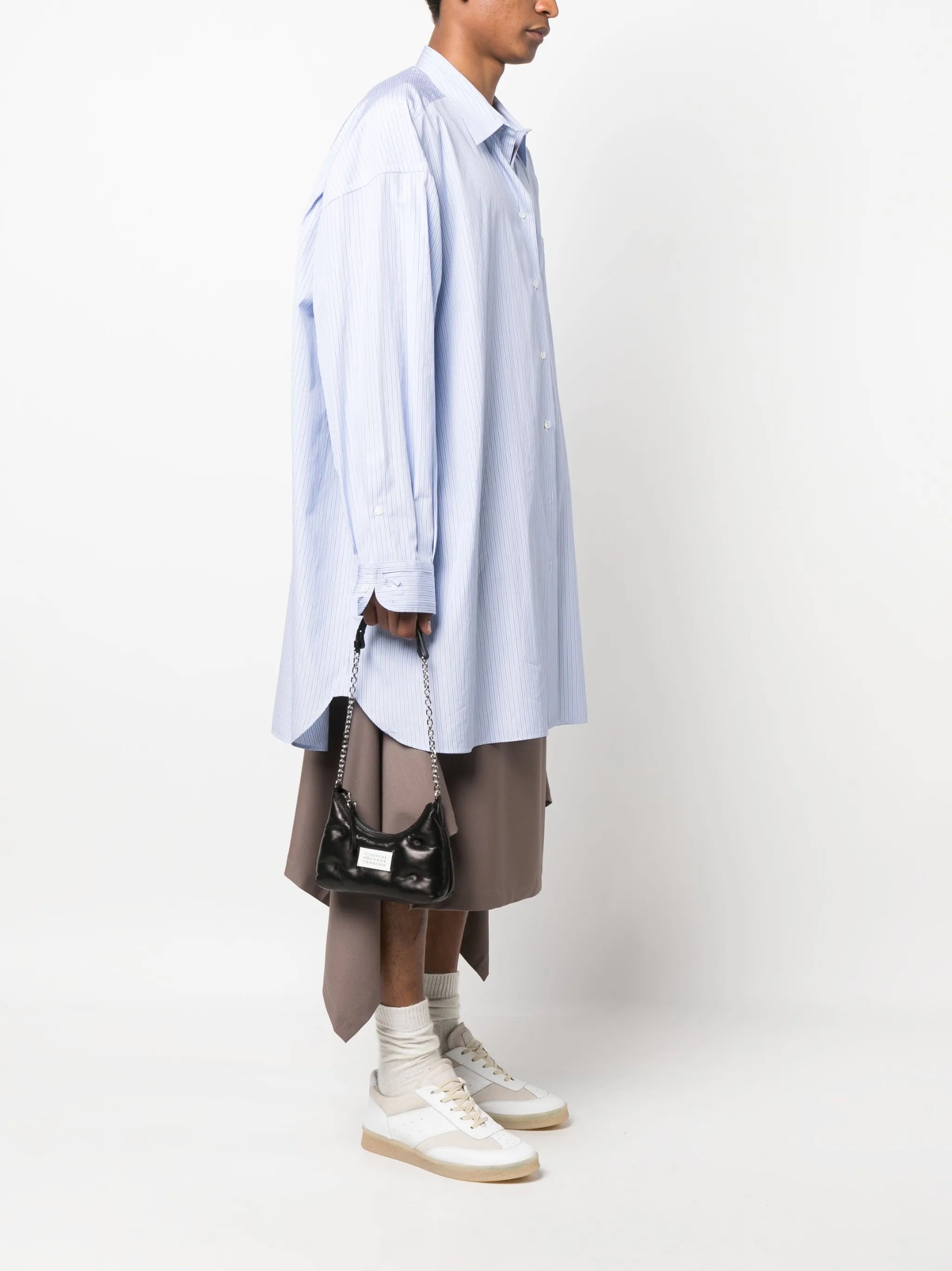 Model holding the Glam Slam Hobo Micro in Black by Maison Margiela, highlighting the padded design and adjustable metal chain shoulder strap.