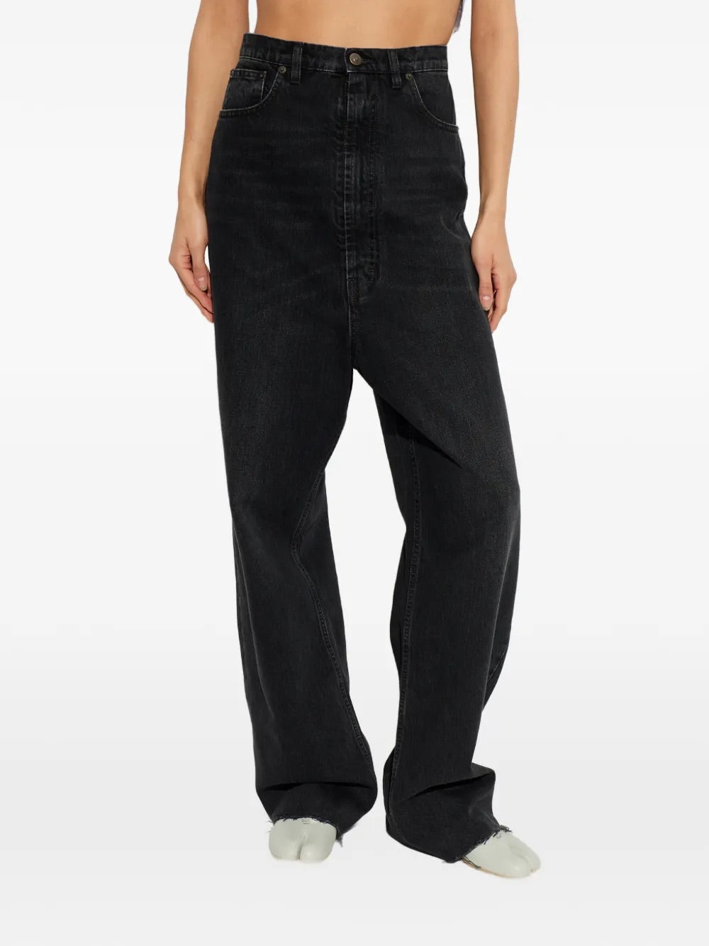 Model wearing Pants 5 Pockets in Medium Black by Maison Margiela, closeup of high waist, button and zip fastening and belt loops on faded medium black denim, Spring/Summer 2026