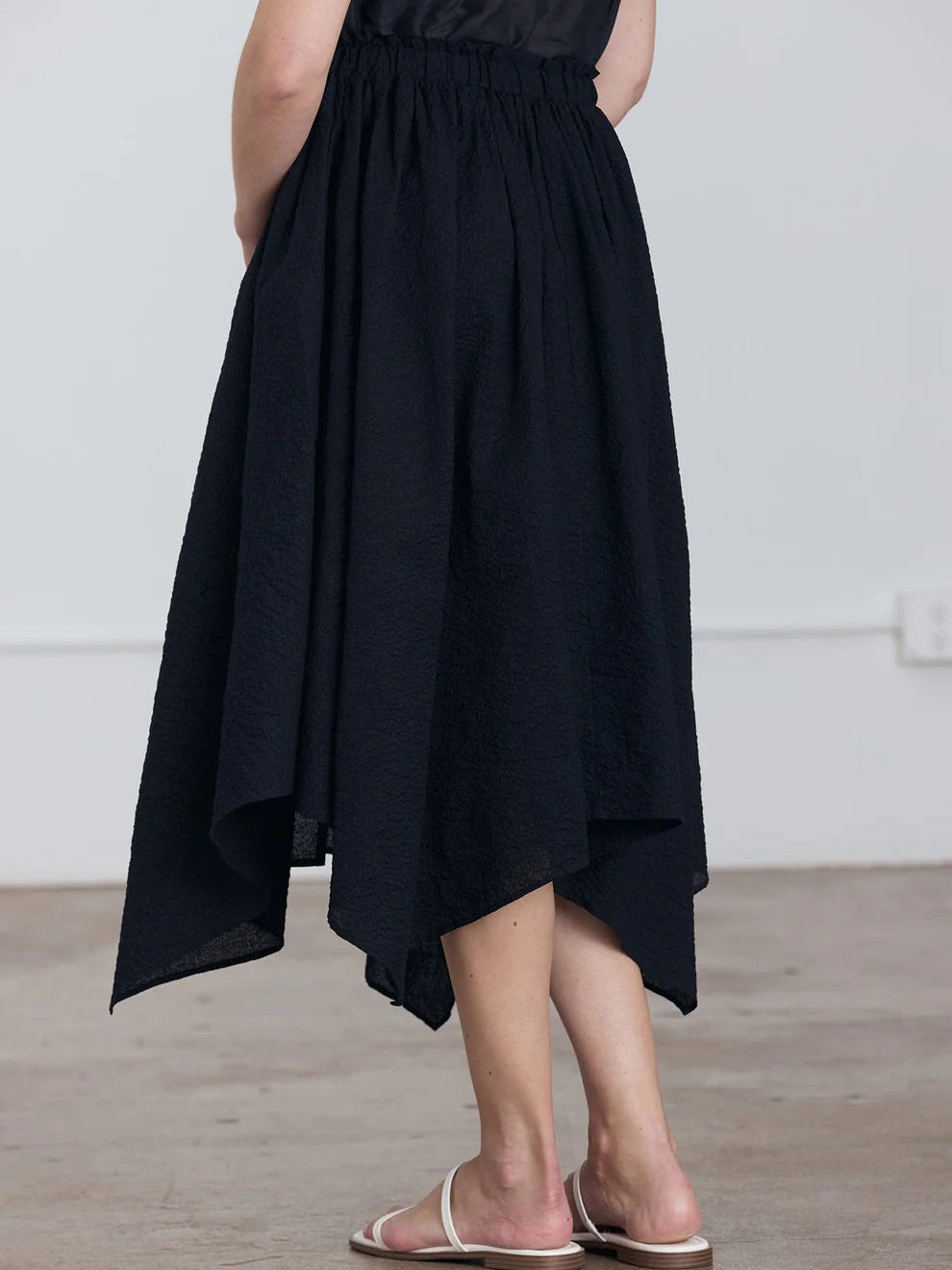 Black Crane Paper Skirt in Midnight - three-quarter back view on model showing voluminous silhouette and asymmetric hem