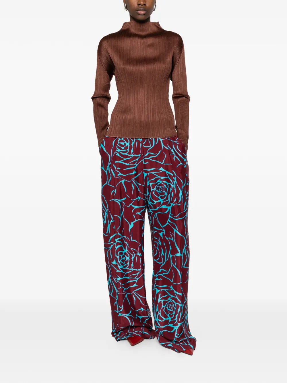 Model wearing the brown, long sleeve, pleated top by Pleats Please Issey Miyake on a white background