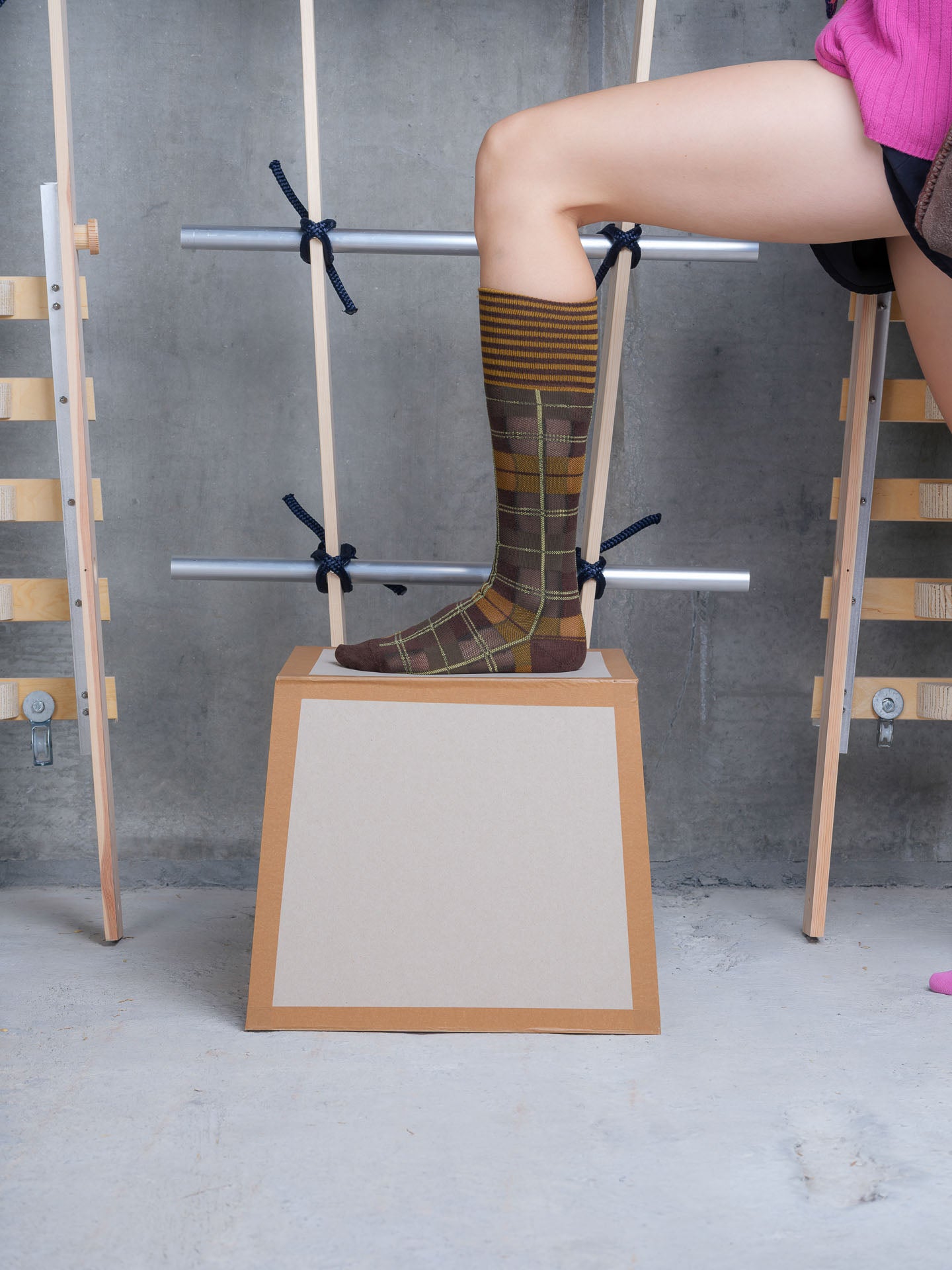 Model wearing Ribbit Knee Sock in Brown Green Dashed Checks by Henrik Vibskov