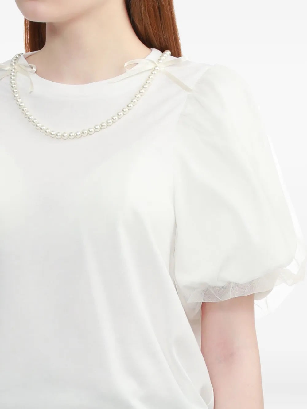White blouse with ruffled sleeves and a pearl necklace on a white background