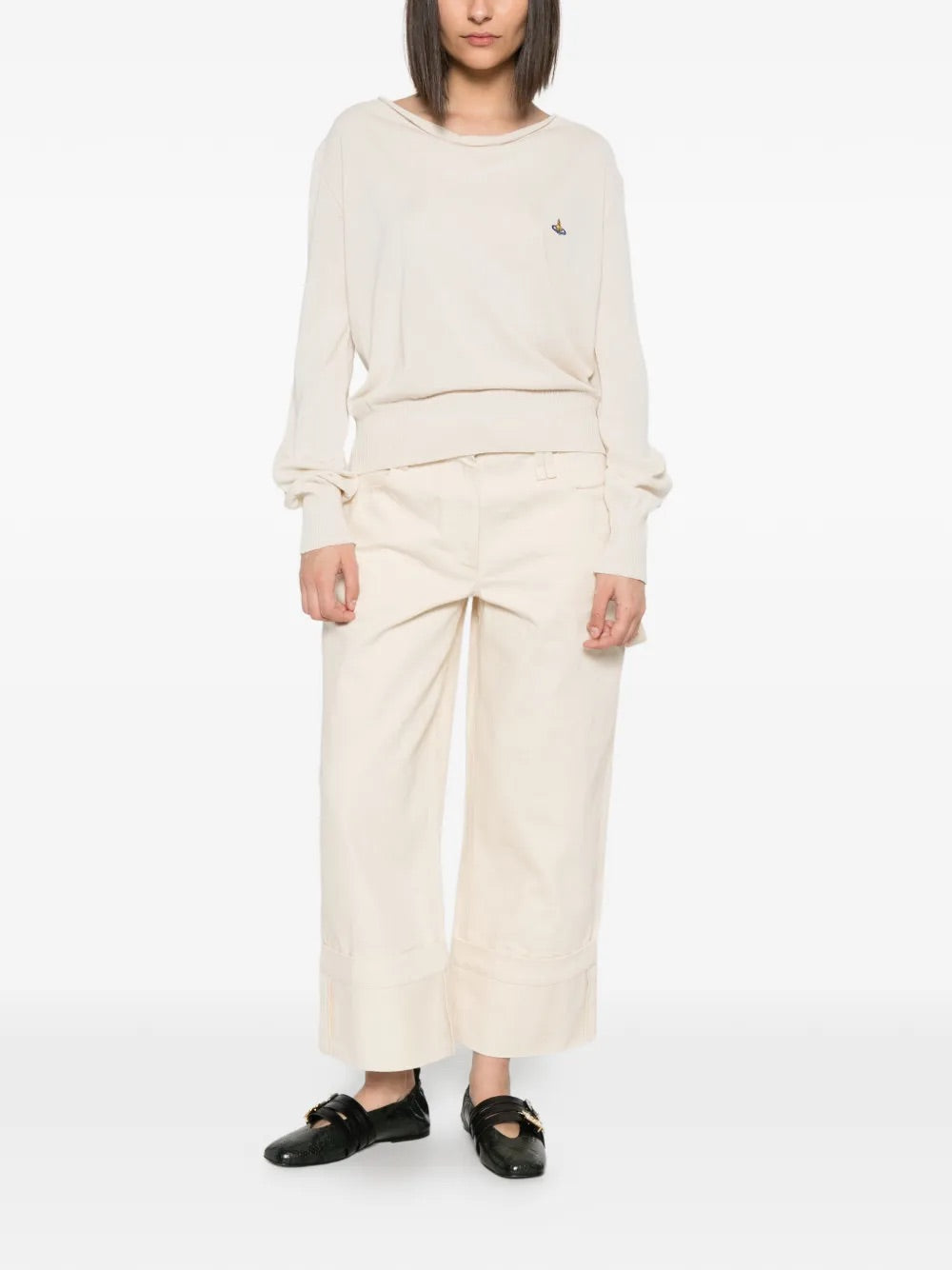 Model wearing Pamela Jumper in Cream by Vivienne Westwood, full-length front view of relaxed-fit cream cotton jumper with draped cowl neck and multicolour Orb embroidery, Spring/Summer 2026