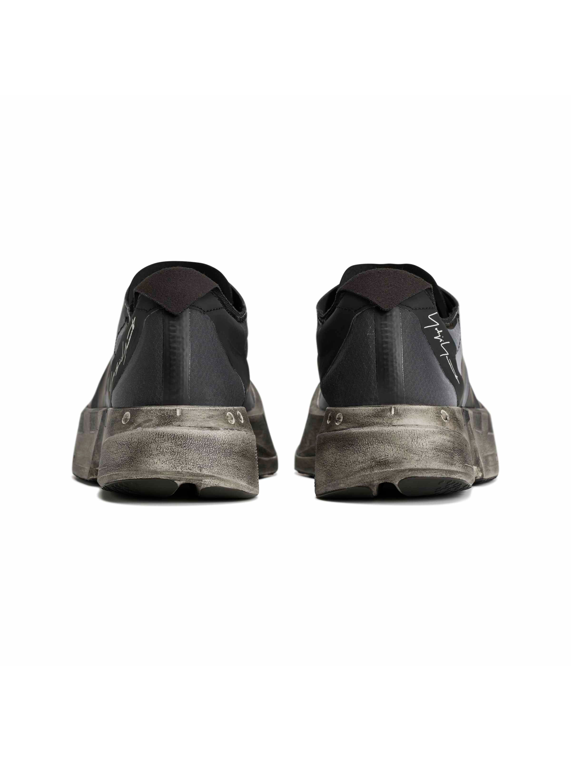 Y-3 Adios Pro 4 rear pair view, heel construction detail, Yohji Yamamoto script signature, black upper, distressed grey midsole