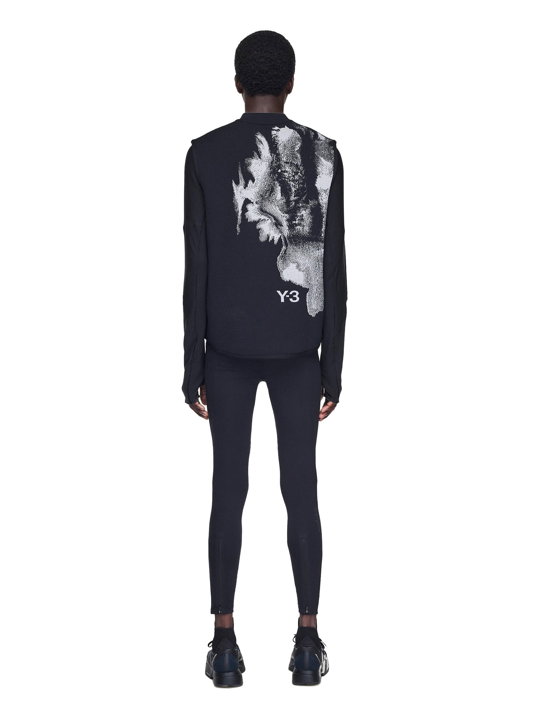 Person wearing a black outfit with a graphic design on the back, featuring the Y3 logo.
