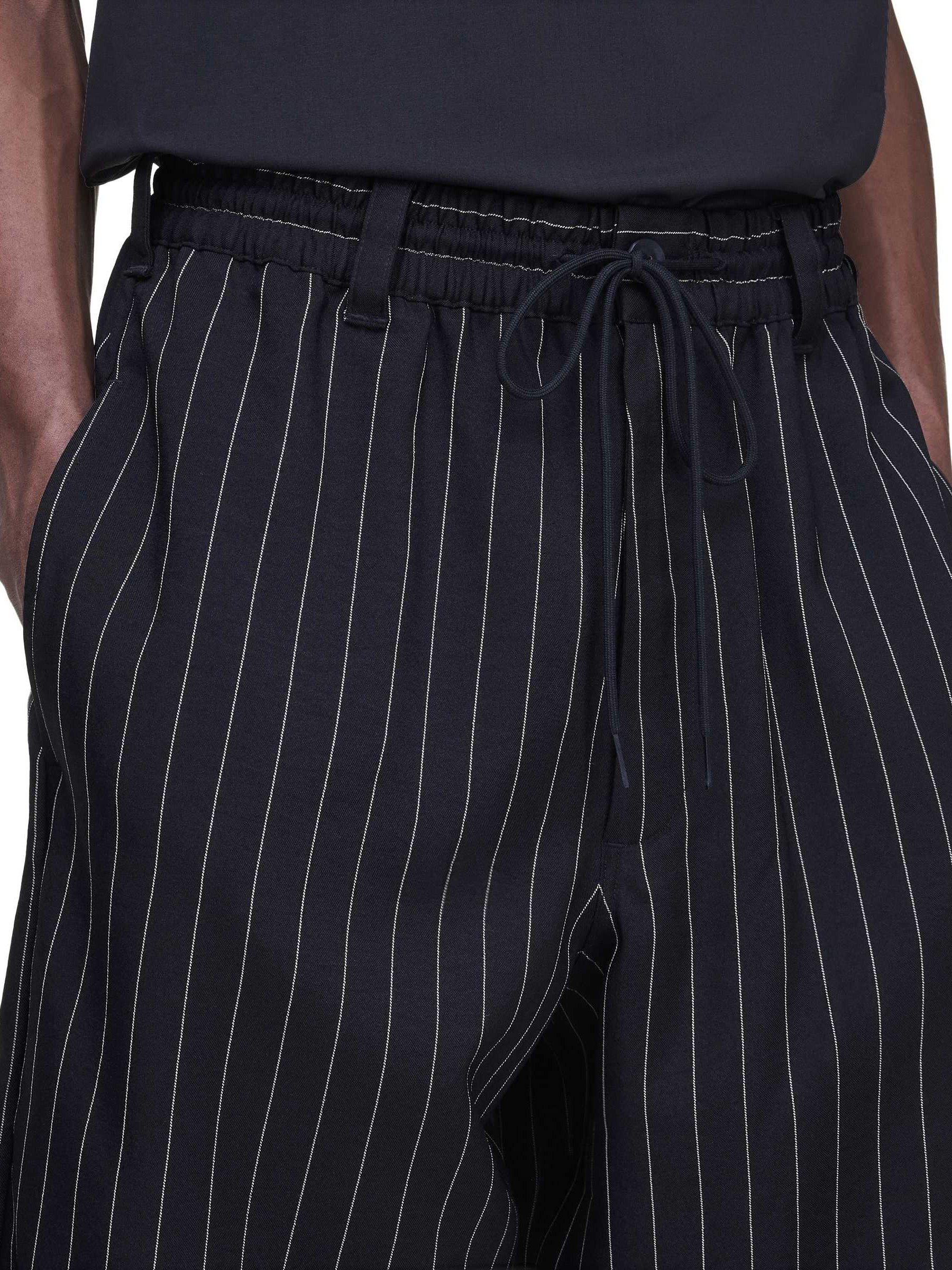 Close-up front view of a male model wearing the Y-3 Pinstripe Sport Uniform Shorts in Black, highlighting the pinstripe detail and contemporary finish.