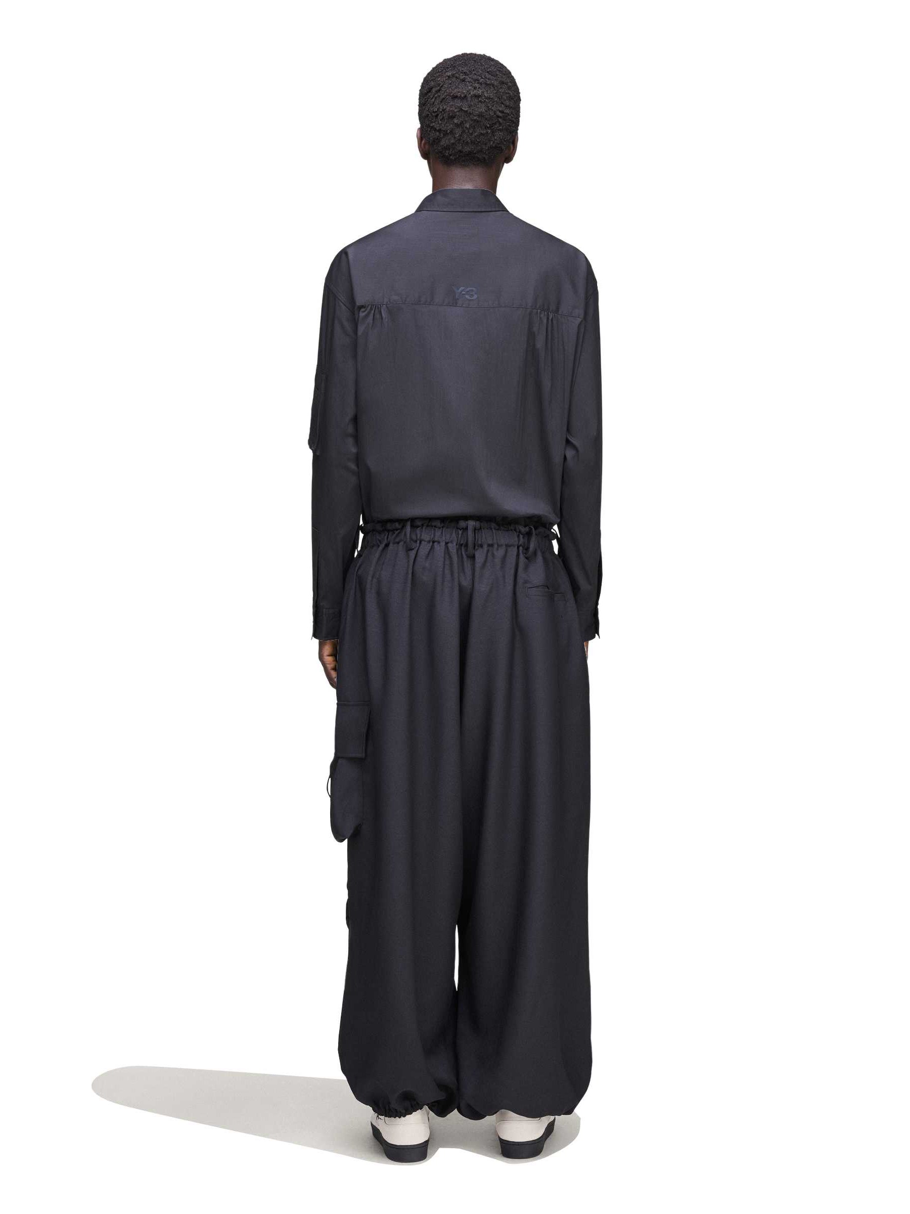 Back view of a male model wearing the Y-3 Sport Uniform Wide Cargo Trousers in Black, showing the rear flap pockets and relaxed fit.