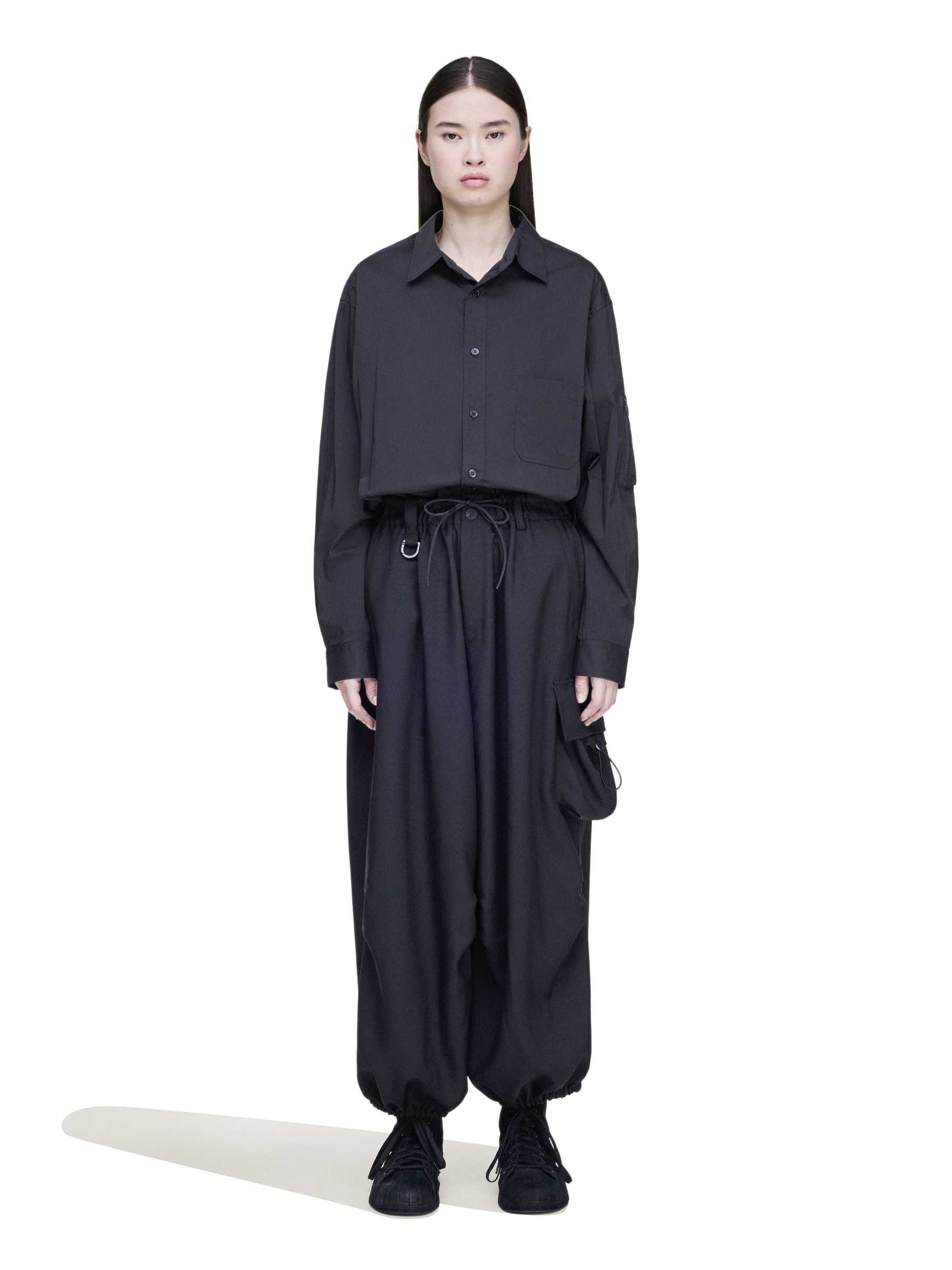 Front view of a female model wearing the Y-3 Sport Uniform Wide Cargo Trousers in Black, highlighting the wide-leg silhouette, elasticised waistband, and functional cargo pockets.
