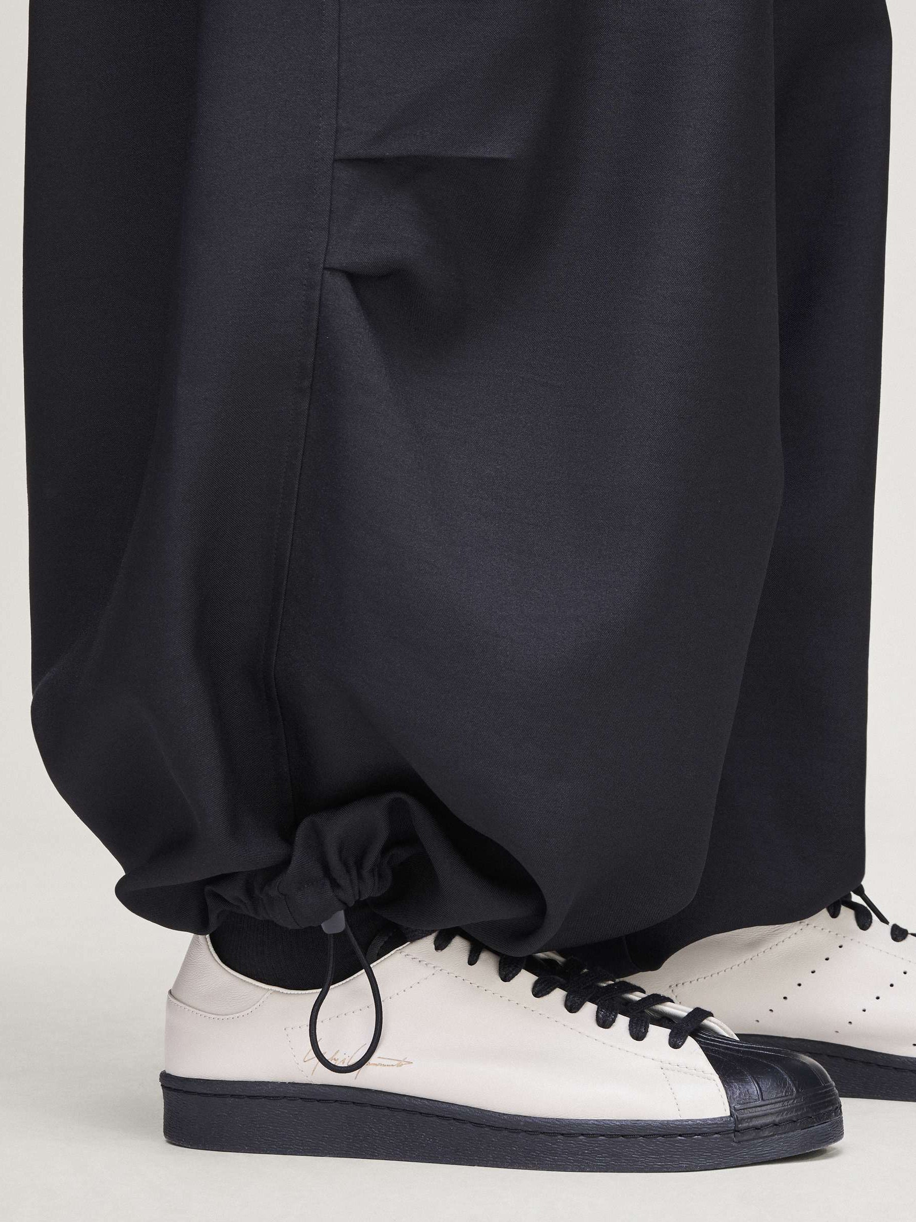 Close-up of the lower leg of the Y-3 Sport Uniform Wide Cargo Trousers in Black on a female model, emphasizing the wide-leg hem and fabric texture.