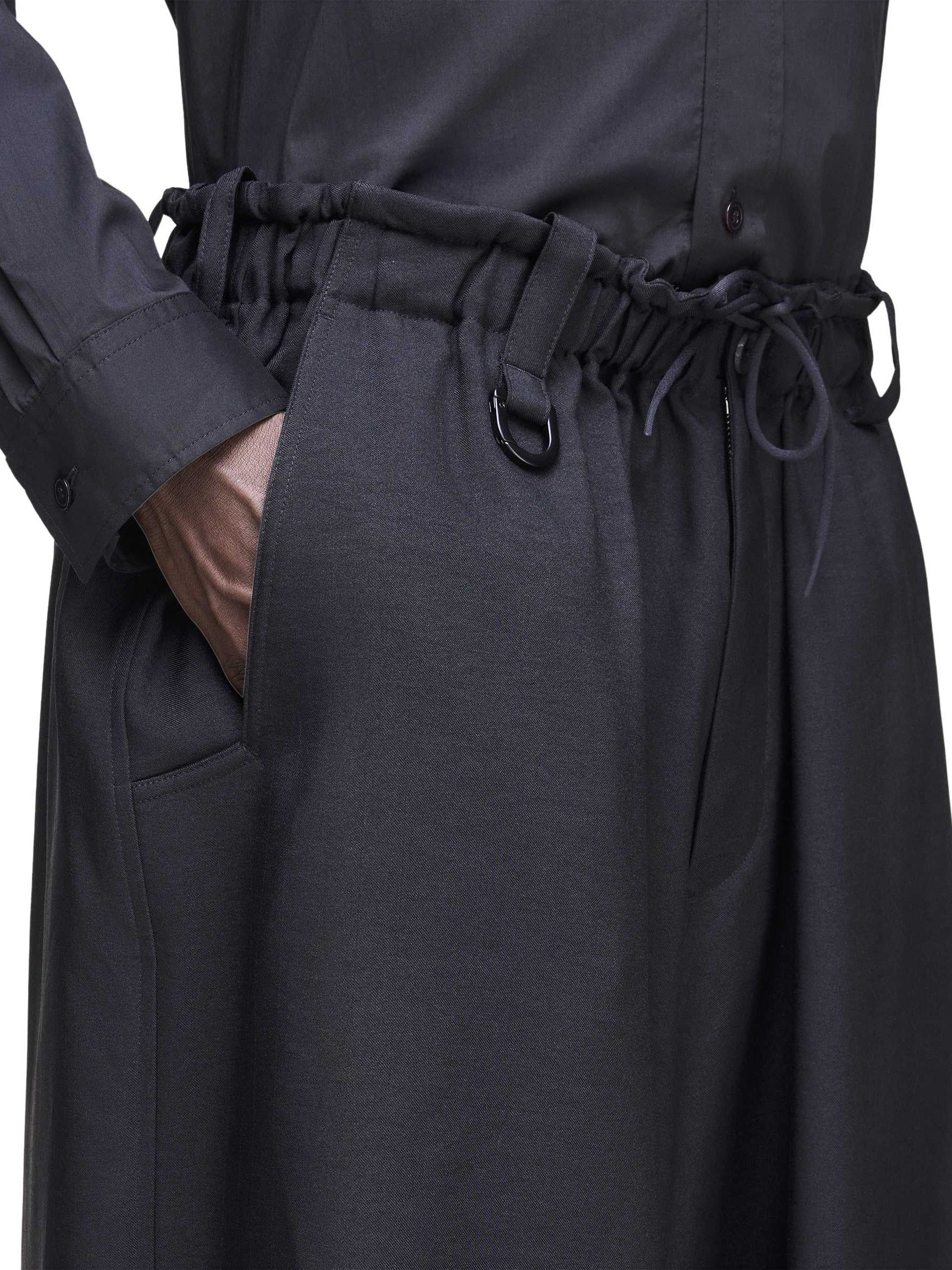 Close-up side view of the Y-3 Sport Uniform Wide Cargo Trousers in Black on a female model, highlighting the cargo flap pockets and D-ring detail.
